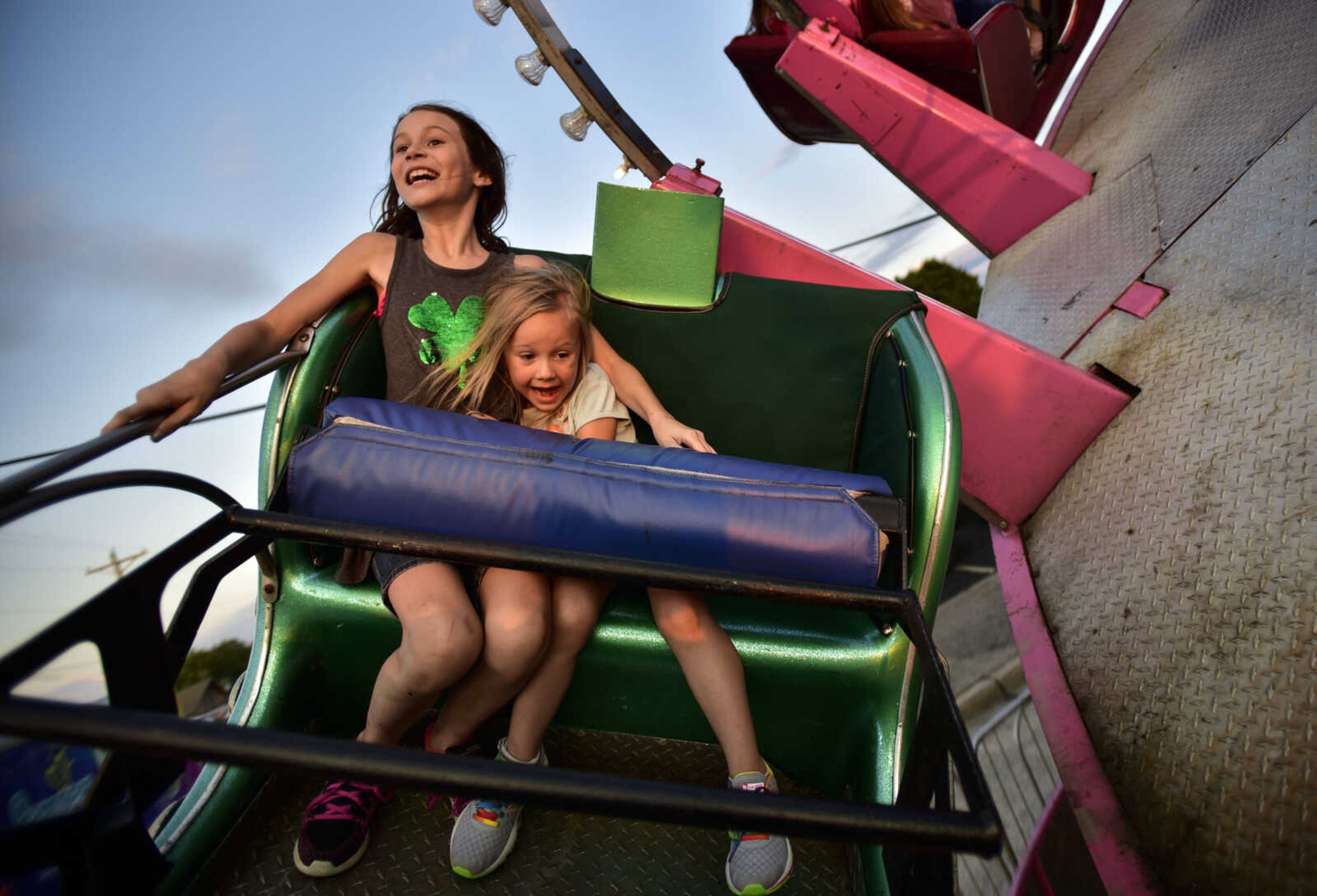 Kendal Daugherty, 4, clutches onto her sister, Lillian, 10, as the "Aladin" ride spins Friday, July 27, 2018 at Homecomers in Jackson.