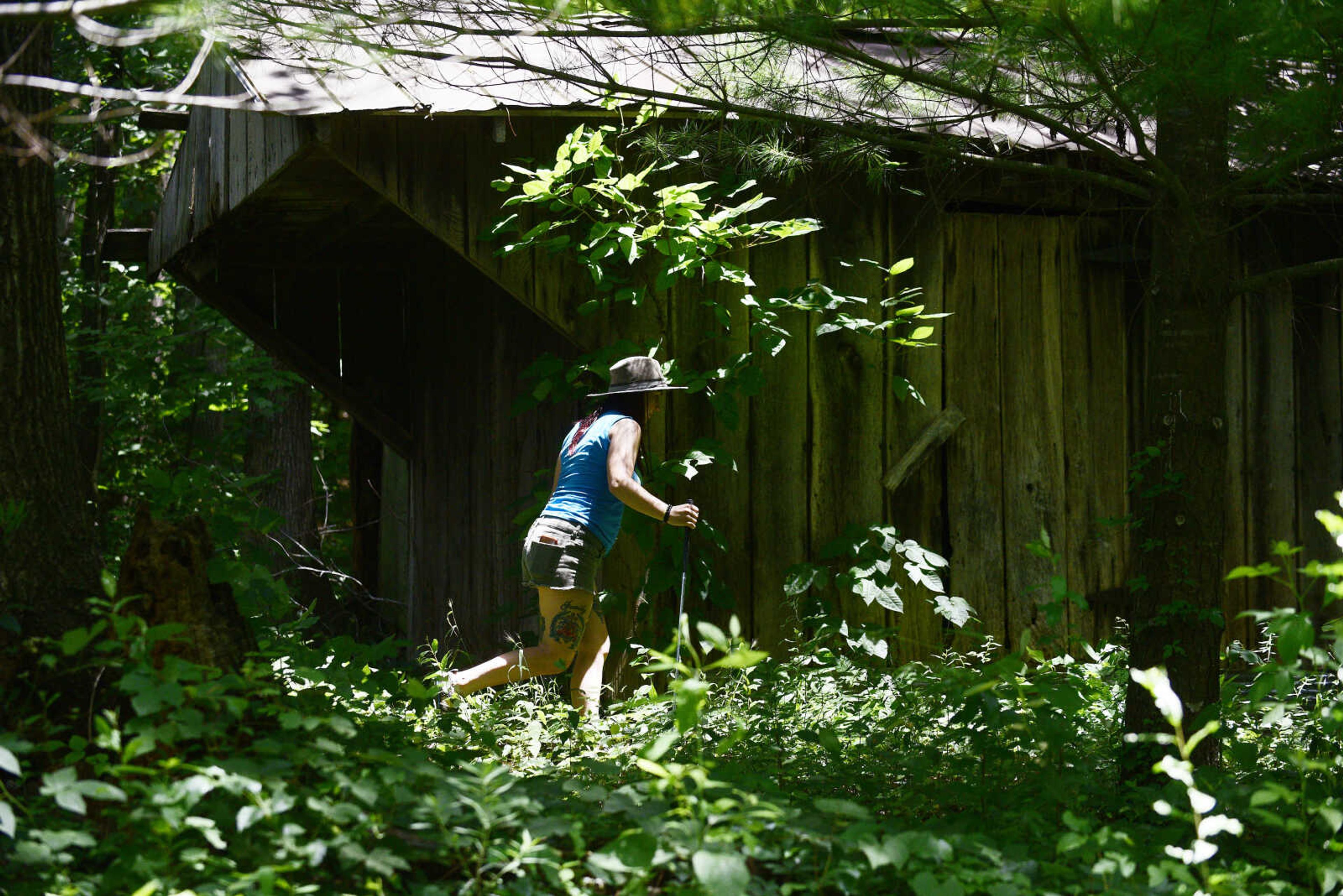 Anna Mae Zembsch checks around an old chicken coup for snakes.