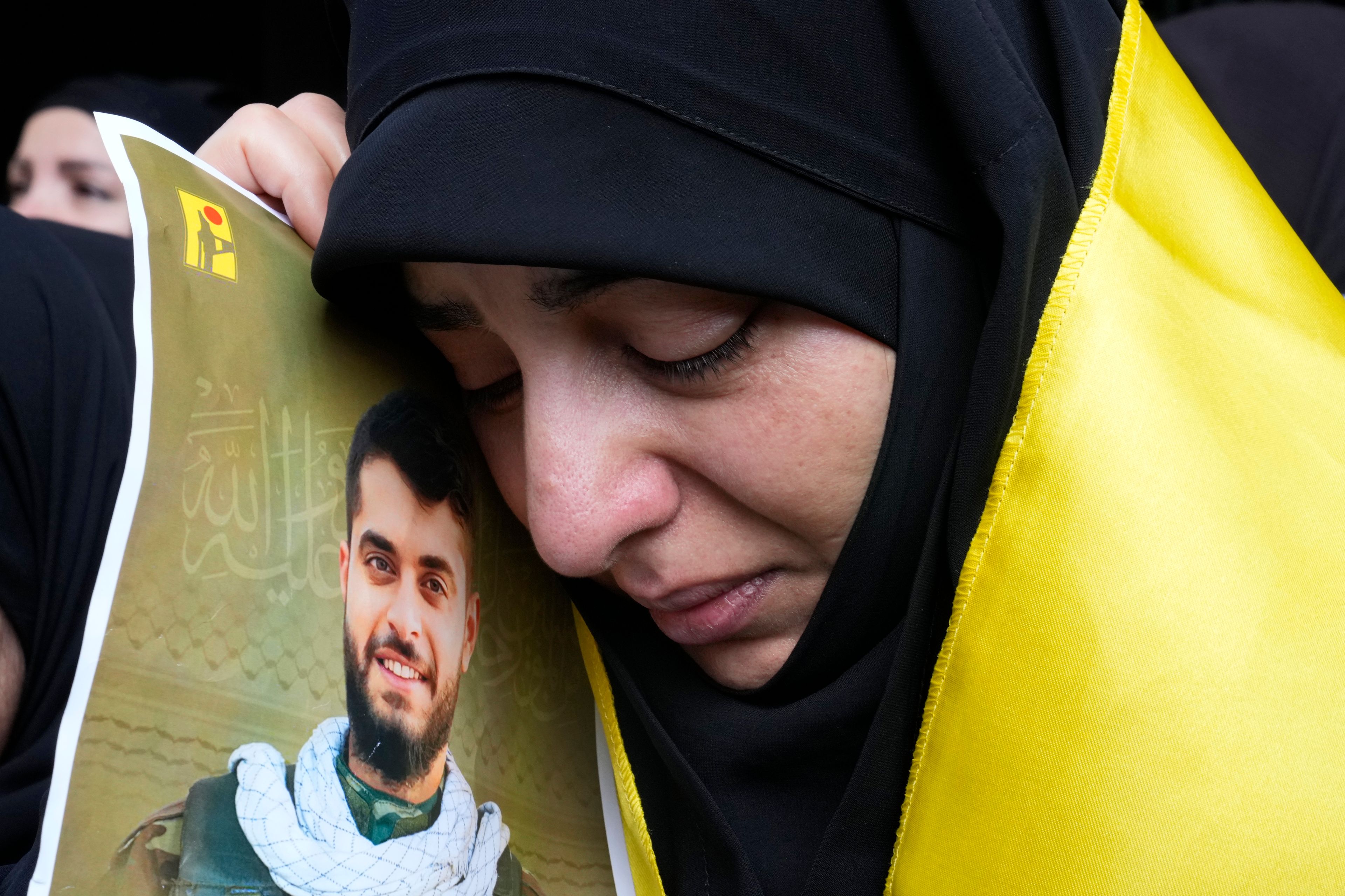 A woman holds a picture of a Hezbollah member who was killed on Wednesday when a handheld device exploded, during his funeral procession in the southern suburbs of Beirut, Thursday, Sept. 19, 2024. (AP Photo/Hussein Malla)