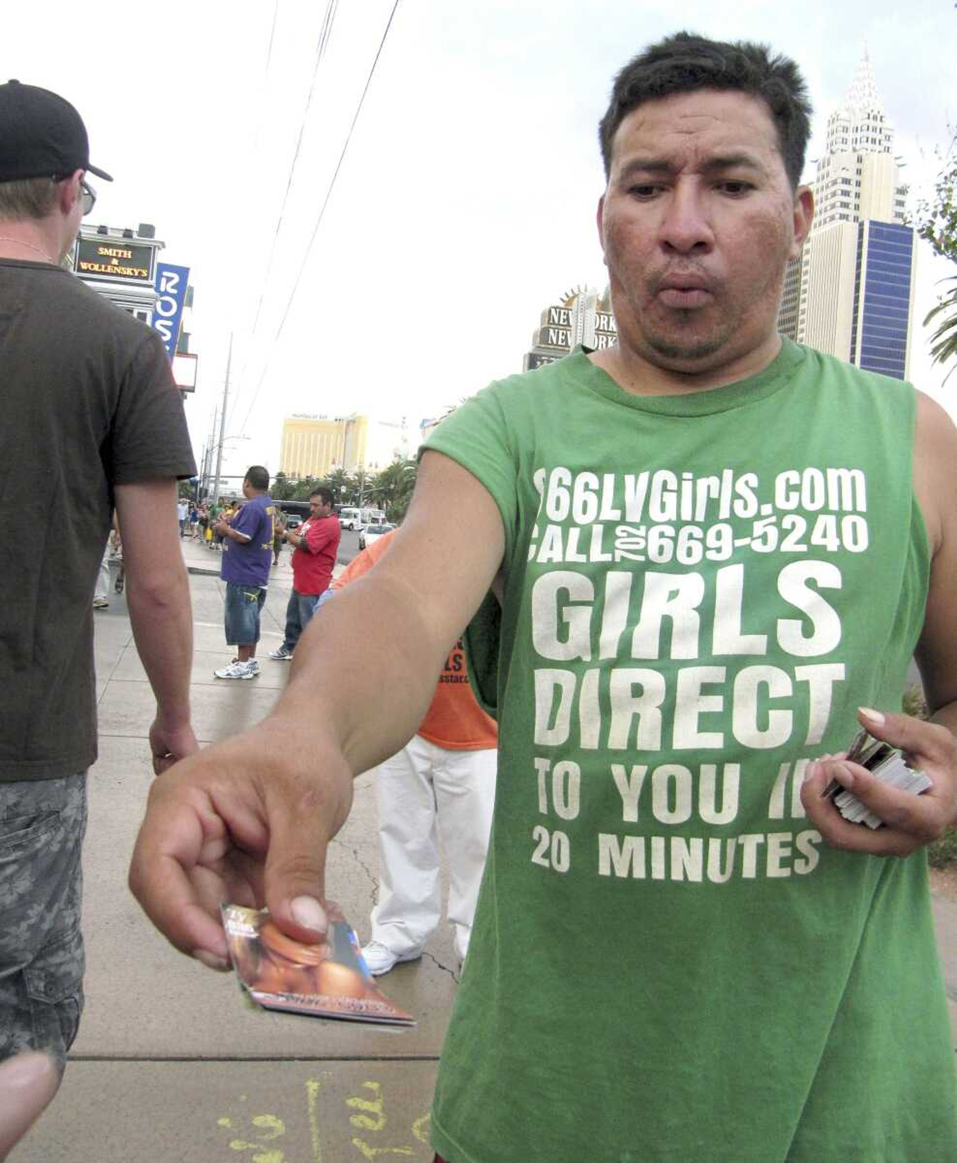 An unidentified man on a Las Vegas Strip sidewalk hands out cards advertising exotic dancers Aug. 29. (Mead Gruver ~ Associated Press)