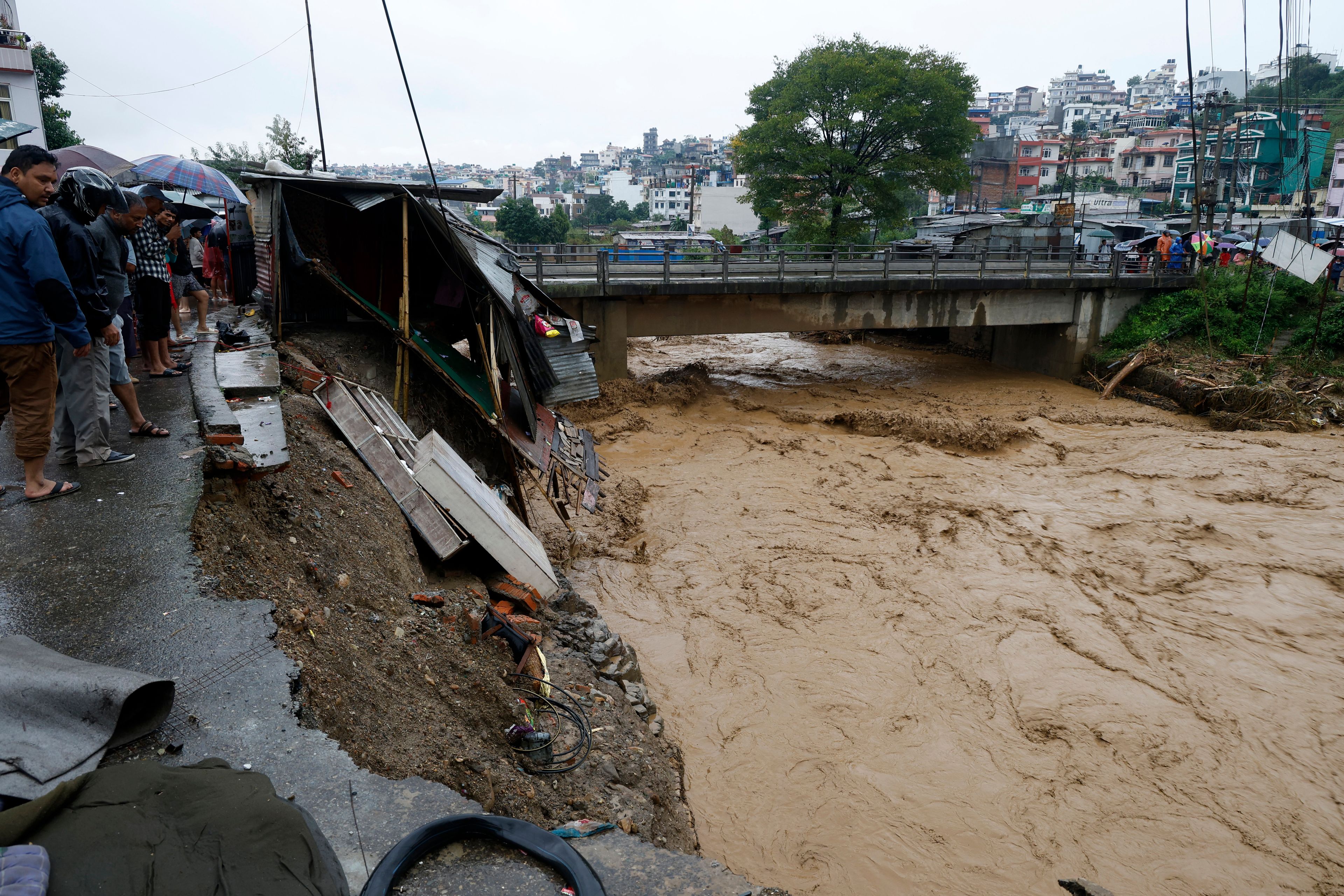 People gather at the edge of the Bagmati River in spate after heavy rains in Kathmandu, Nepal, Saturday, Sept. 28, 2024. (AP Photo/Gopen Rai)