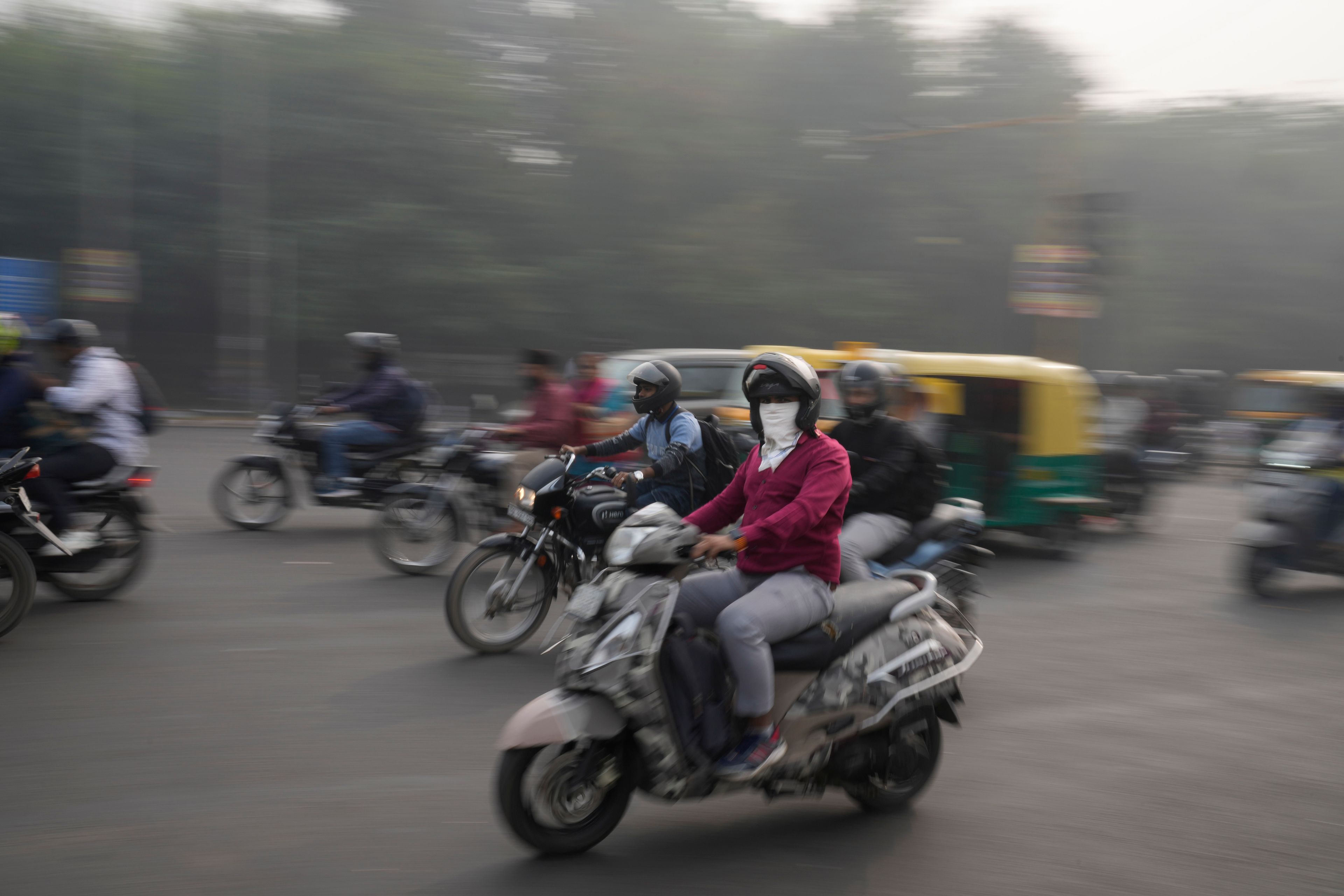 A commuter wearing a mask rides on a road enveloped by smog in New Delhi, India, Thursday, Nov. 14, 2024. (AP Photo/Manish Swarup)