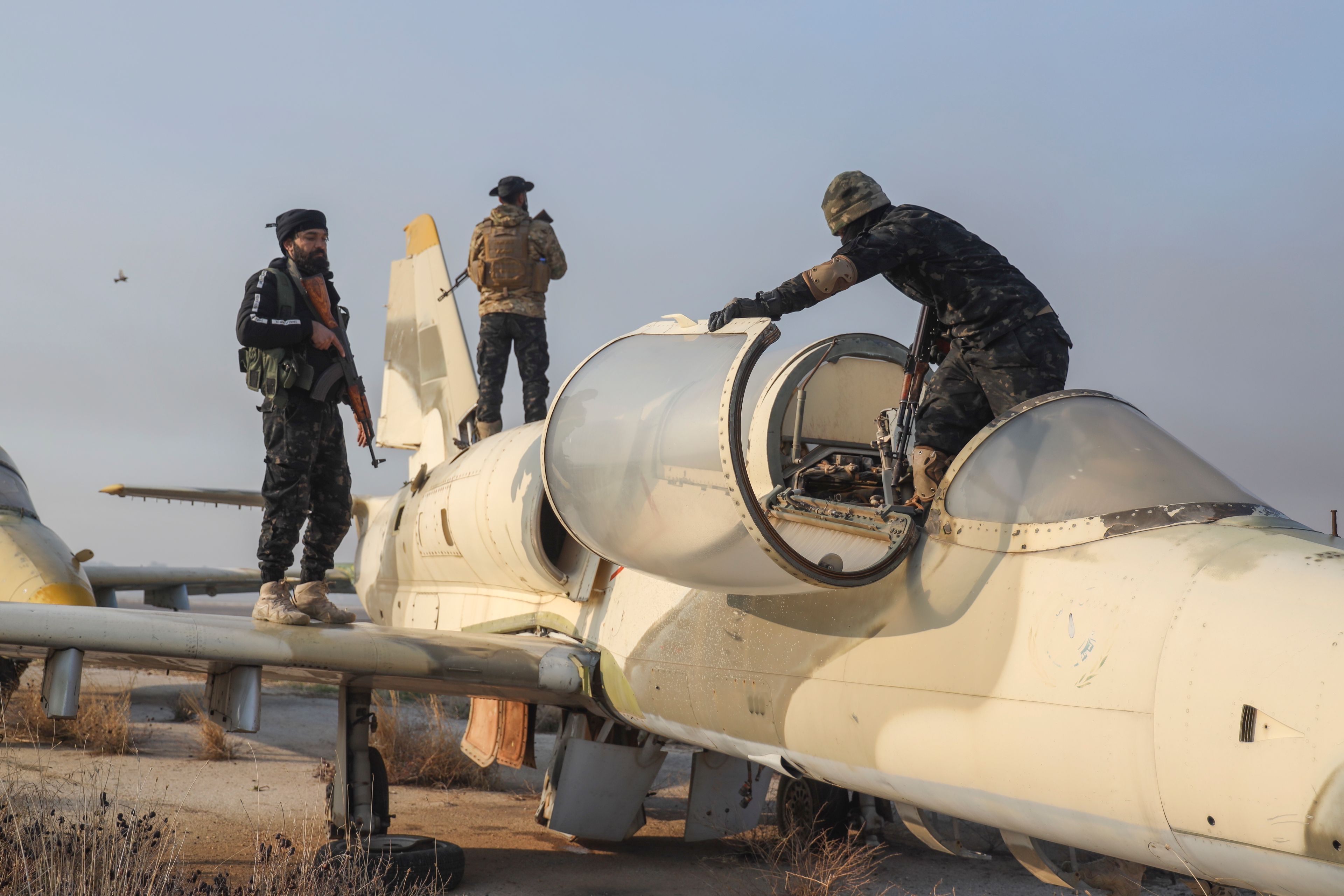 Syrian opposition fighters stand on an aircraft at the Al-Nayrab military airport after they took control of the facility in the outskirts of Aleppo, Syria, Monday, Dec. 2, 2024. .(AP Photo/Omar Albam)