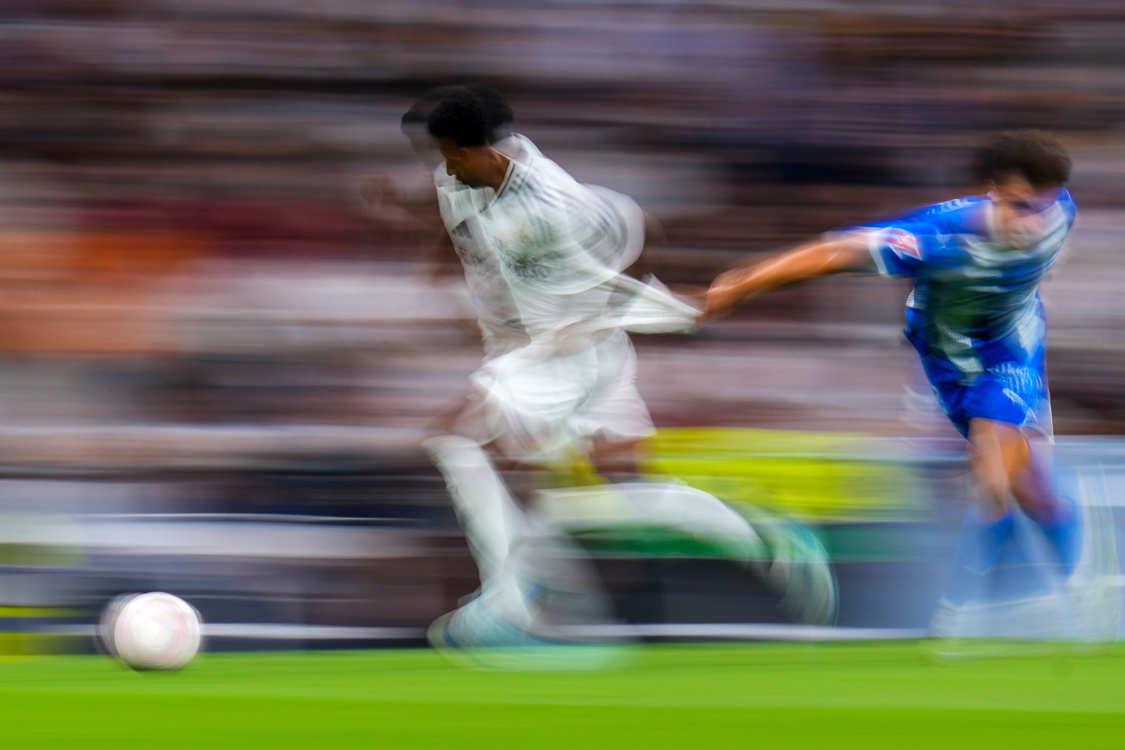 In this image taken with a slow shutter speed, Real Madrid's Rodrygo, left, duels for the ball with Alaves' Carlos Benavidez during a Spanish La Liga soccer match between Real Madrid and Alaves at Santiago Bernabeu stadium in Madrid, Spain, Tuesday, Sept. 24, 2024. (AP Photo/Manu Fernandez)