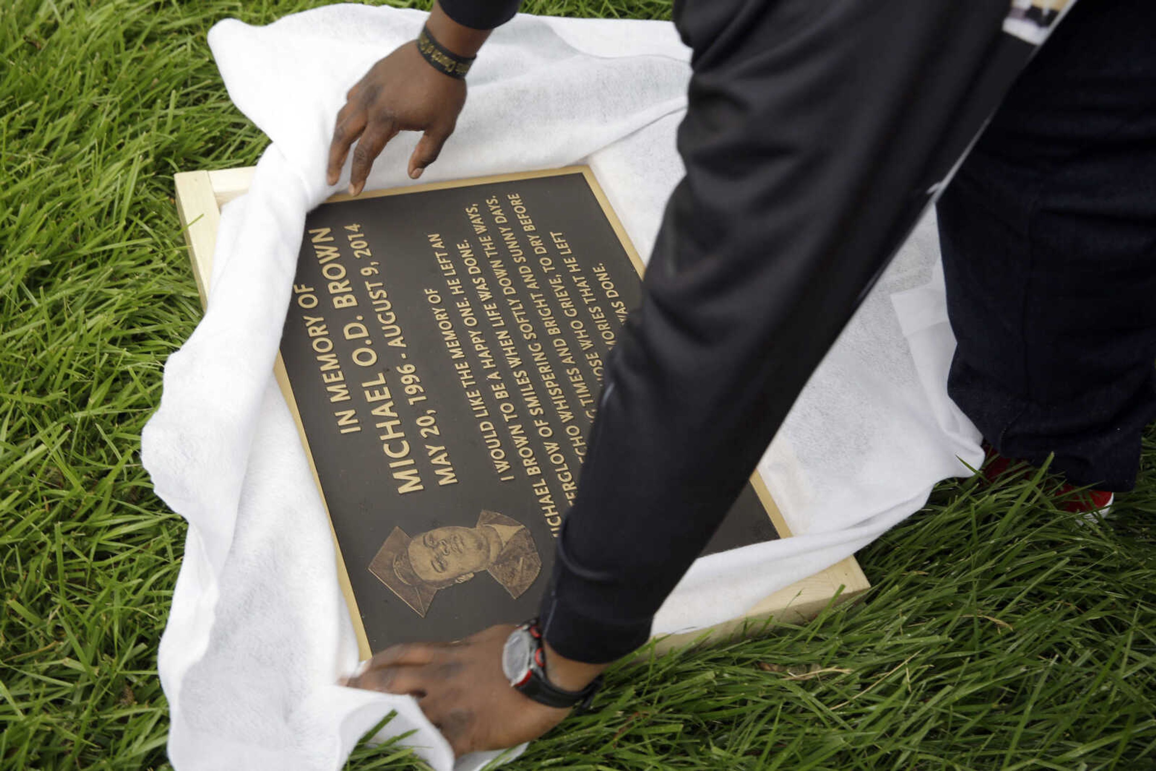 Michael Brown Sr. unwraps a plaque remembering his son, Michael Brown, to show volunteers as they remove items left at a makeshift memorial to Michael Brown on Wednesday in Ferguson, Missouri. The memorial that has marked the place where Brown was fatally shot by a police officer in August has been removed and will be replaced with a permanent plaque. (AP Photo/Jeff Roberson)