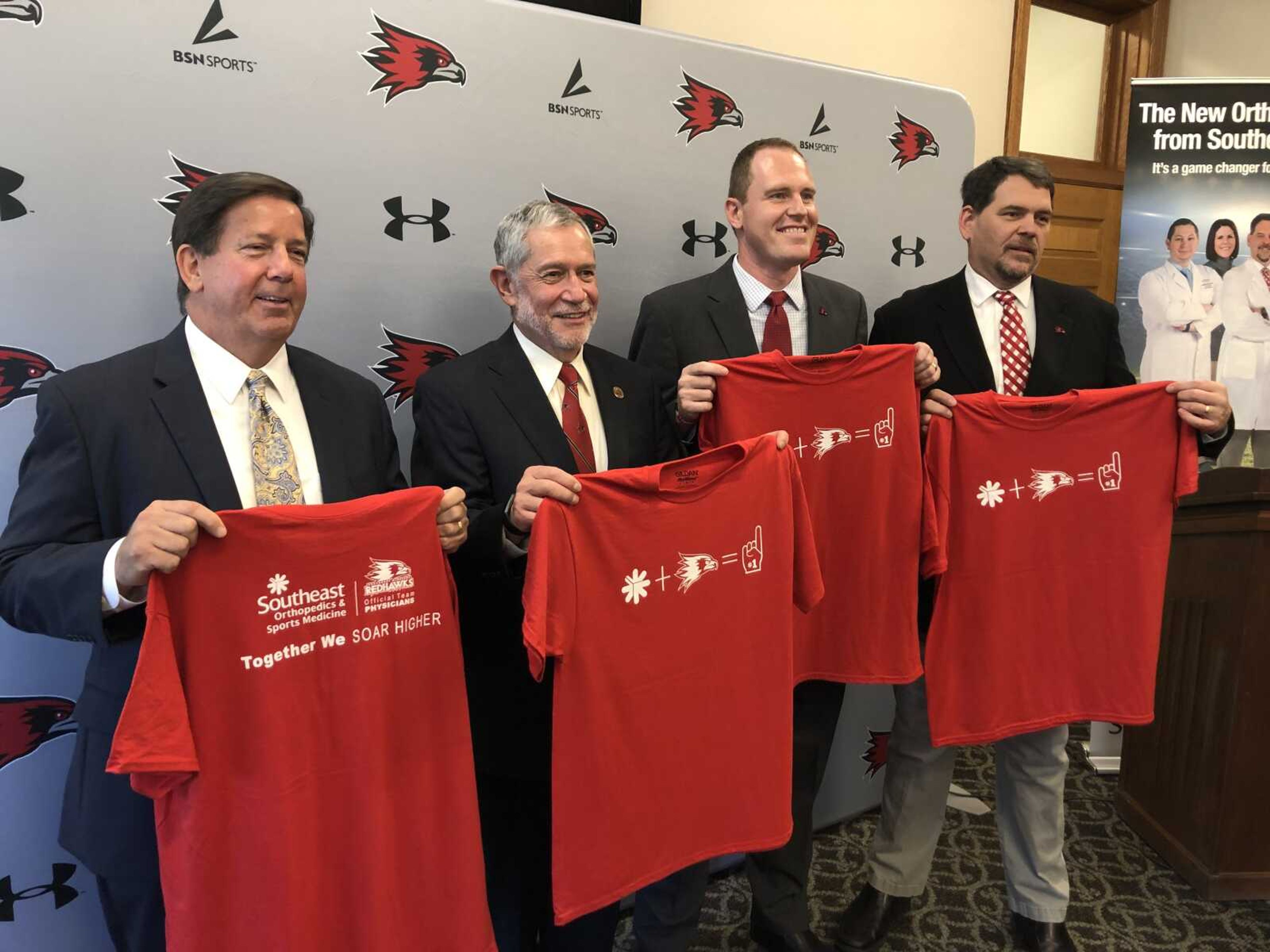 SoutheastHEALTH president and CEO Ken Bateman, left, Southeast Missouri State president Dr. Carlos Vargas, Southeast  athletics director Brady Barke and SoutheastHEALTH orthopedic physician Dr. Anthony McPherron hold T-shirts commemorating a new partnership between Southeast and SoutheastHEALTH.