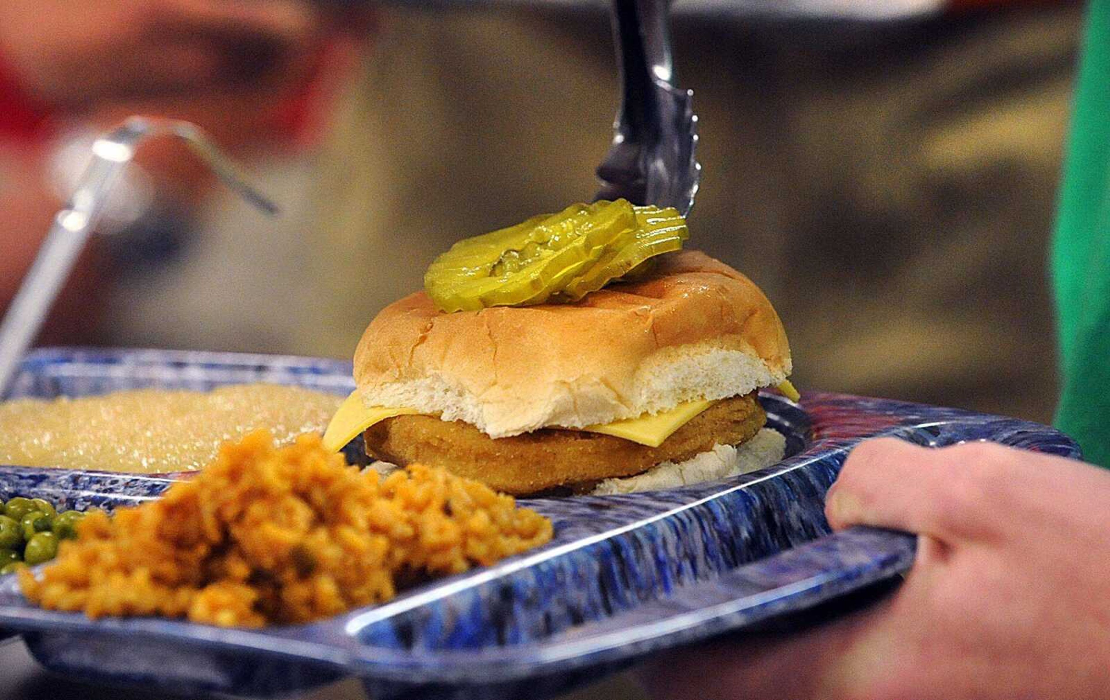 A student tops his chicken sandwich with pickles Sept. 4 at Notre Dame Regional High School. (Laura Simon)