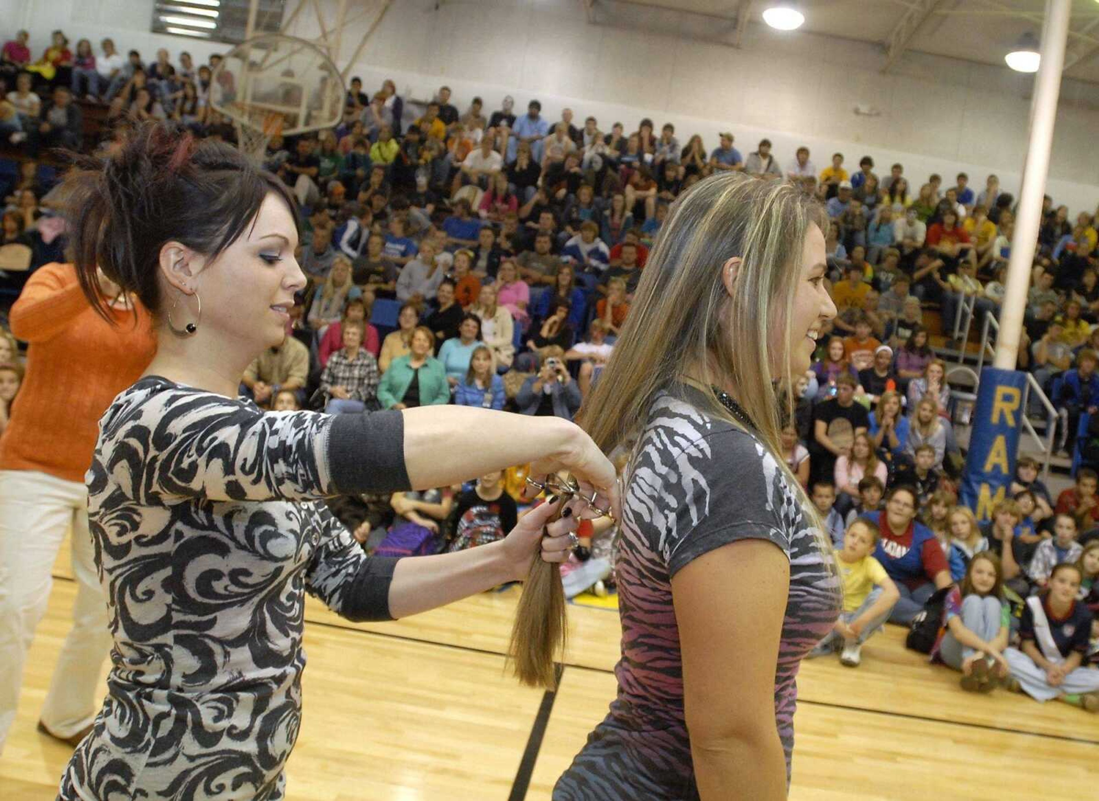 Sara Bradshaw, a seventh-and eighth-grade science teacher in Scott City, gets a section of her hair cut off by Cortney Stubenrauch, of Style Studio, during an assembly at Scott City High School on Friday, Oct. 29, 2010. Bradshaw was joined by students in donating their hair to Locks of Love. Bradshaw organized the donation in honor of her student Taylor Dudley, who has survived the most severe level of non-Hodgkin's lymphoma. (Kristin Eberts)