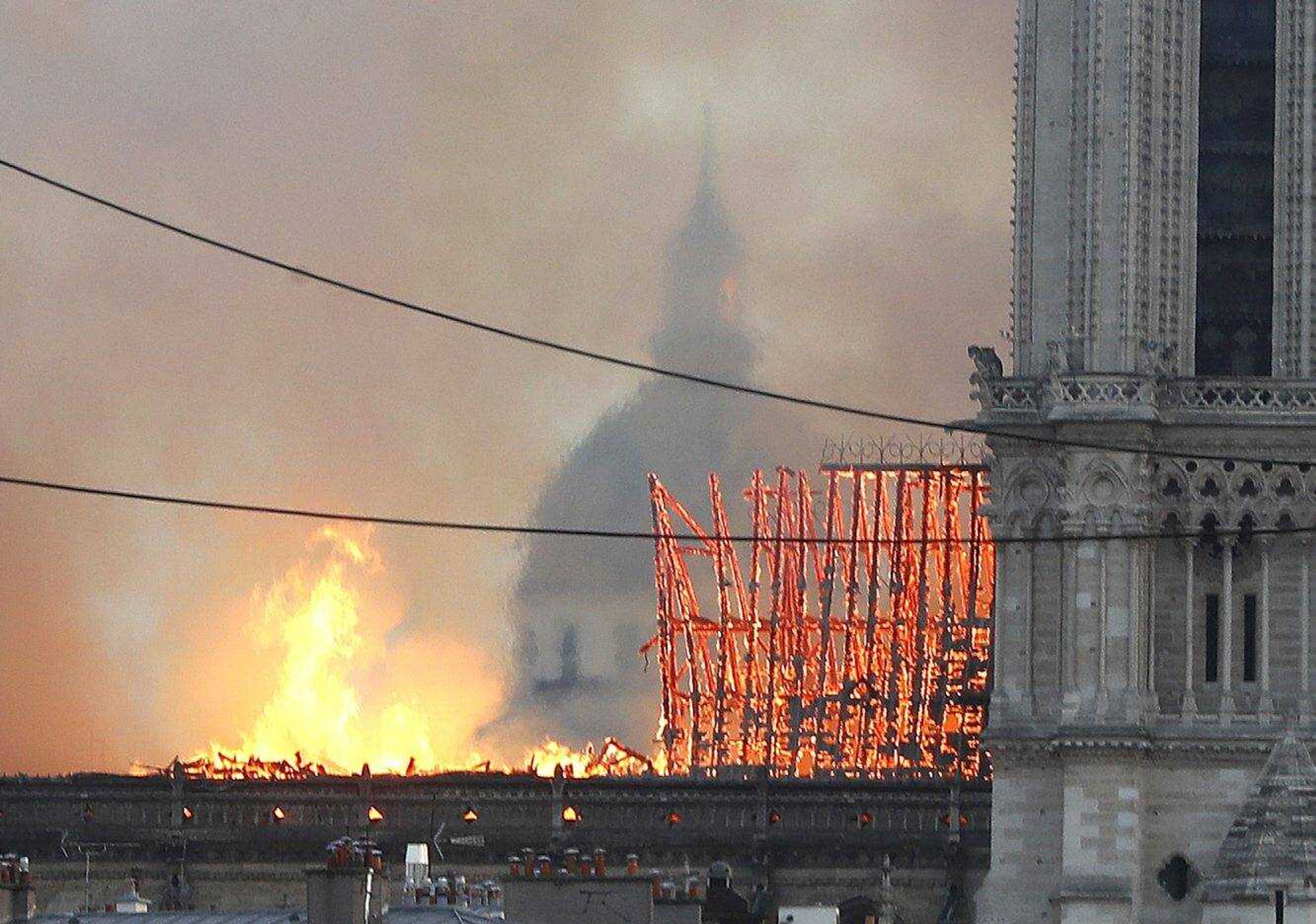 Flames rise from Notre Dame cathedral as it burns in Paris, Monday, April 15, 2019. Massive plumes of yellow brown smoke is filling the air above Notre Dame Cathedral and ash is falling on tourists and others around the island that marks the center of Paris. (AP Photo/Thibault Camus)