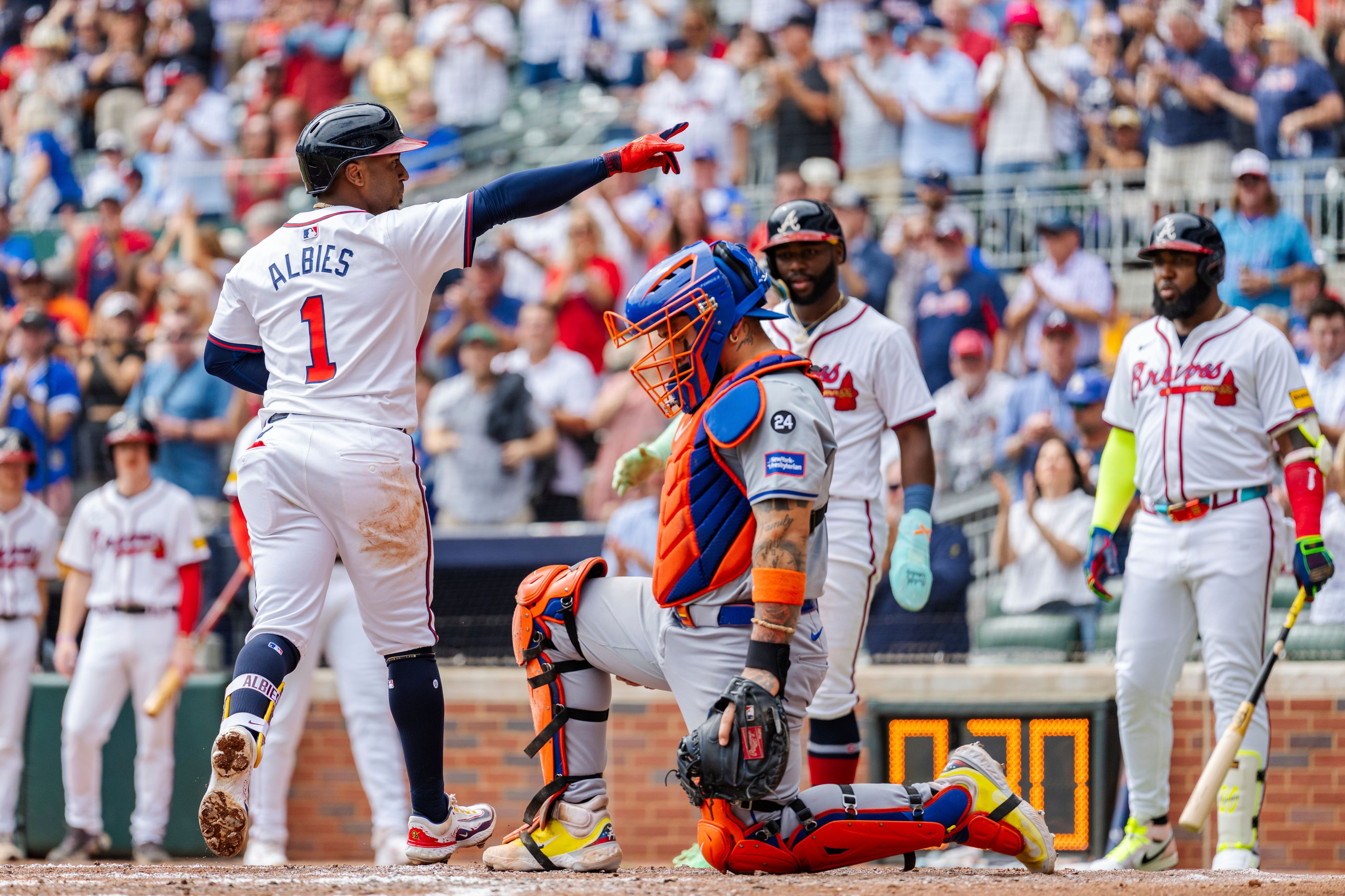 Atlanta Braves' Ozzie Albies, left, gestures to the crowd while stepping on home plate after hitting a two-run home run in the third inning of a baseball game against the New York Mets, Monday, Sept. 30, 2024, in Atlanta. (AP Photo/Jason Allen)