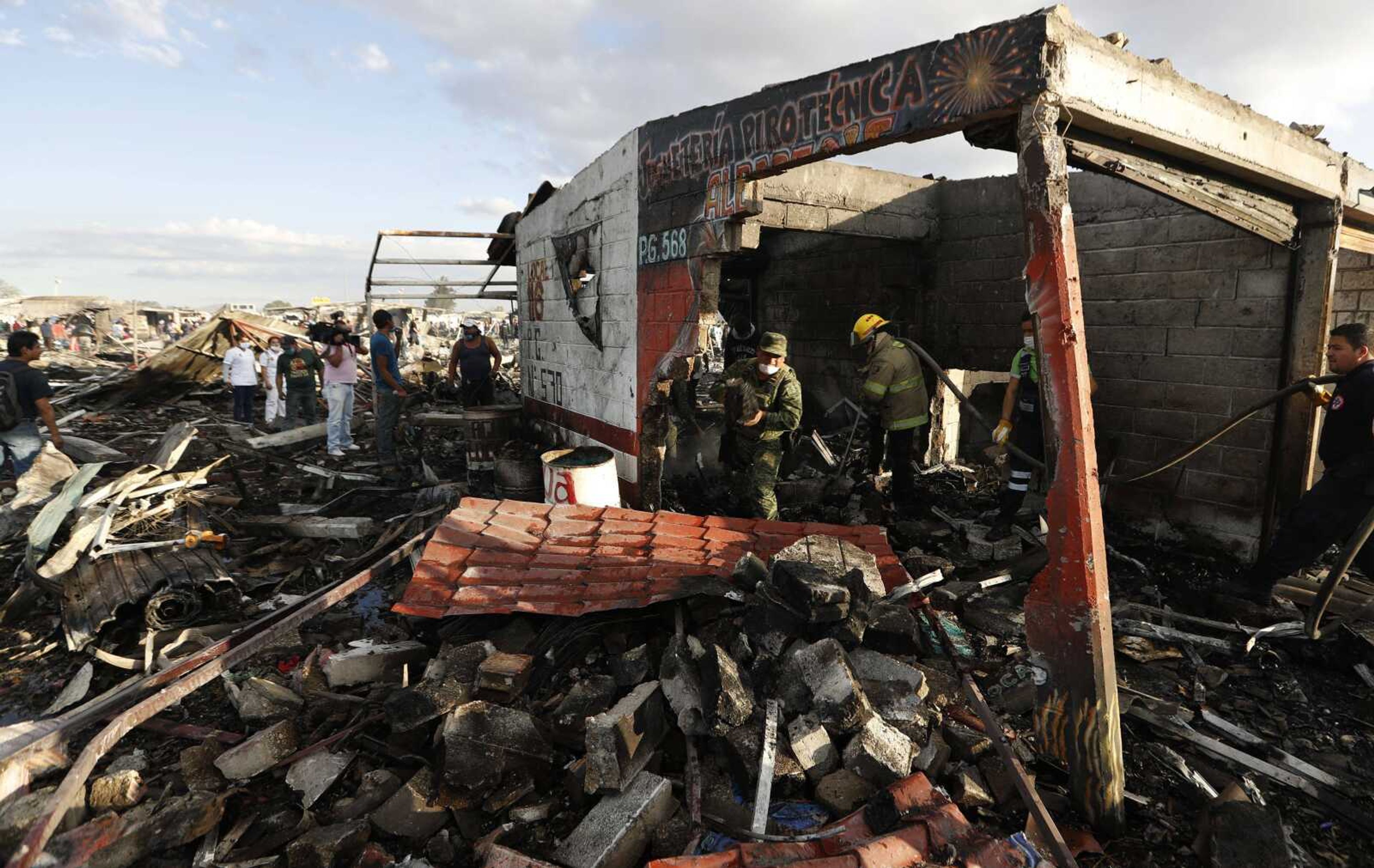 Firefighters and rescue workers comb through ashes and rubble Tuesday at the open-air San Pablito fireworks market in Tultepec, outskirts of Mexico City.