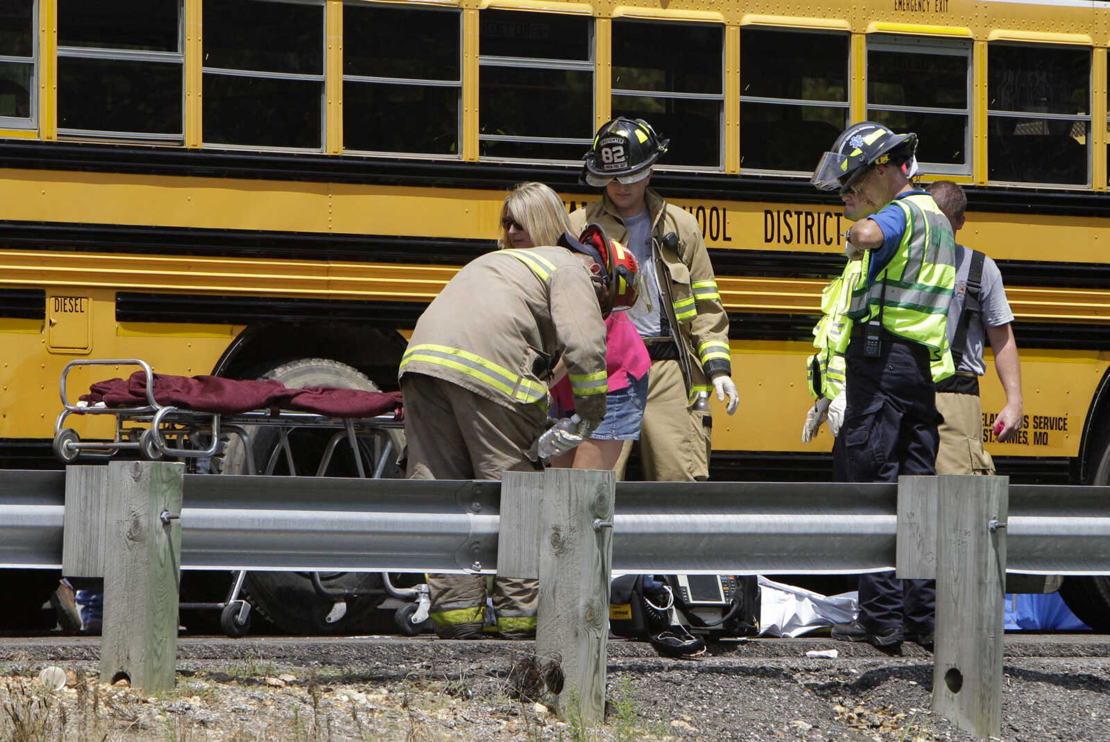 Rescue personnel work on the scene next to the covered body of a passenger killed in an accident involving two school buses, a tractor trailer cab and a pickup truck, Thursday, Aug. 5, 2010, on eastbound Interstate 44 near Gray Summit, Mo. The school buses were carrying high school band students to an amusement park. (AP Photo/Jeff Roberson)