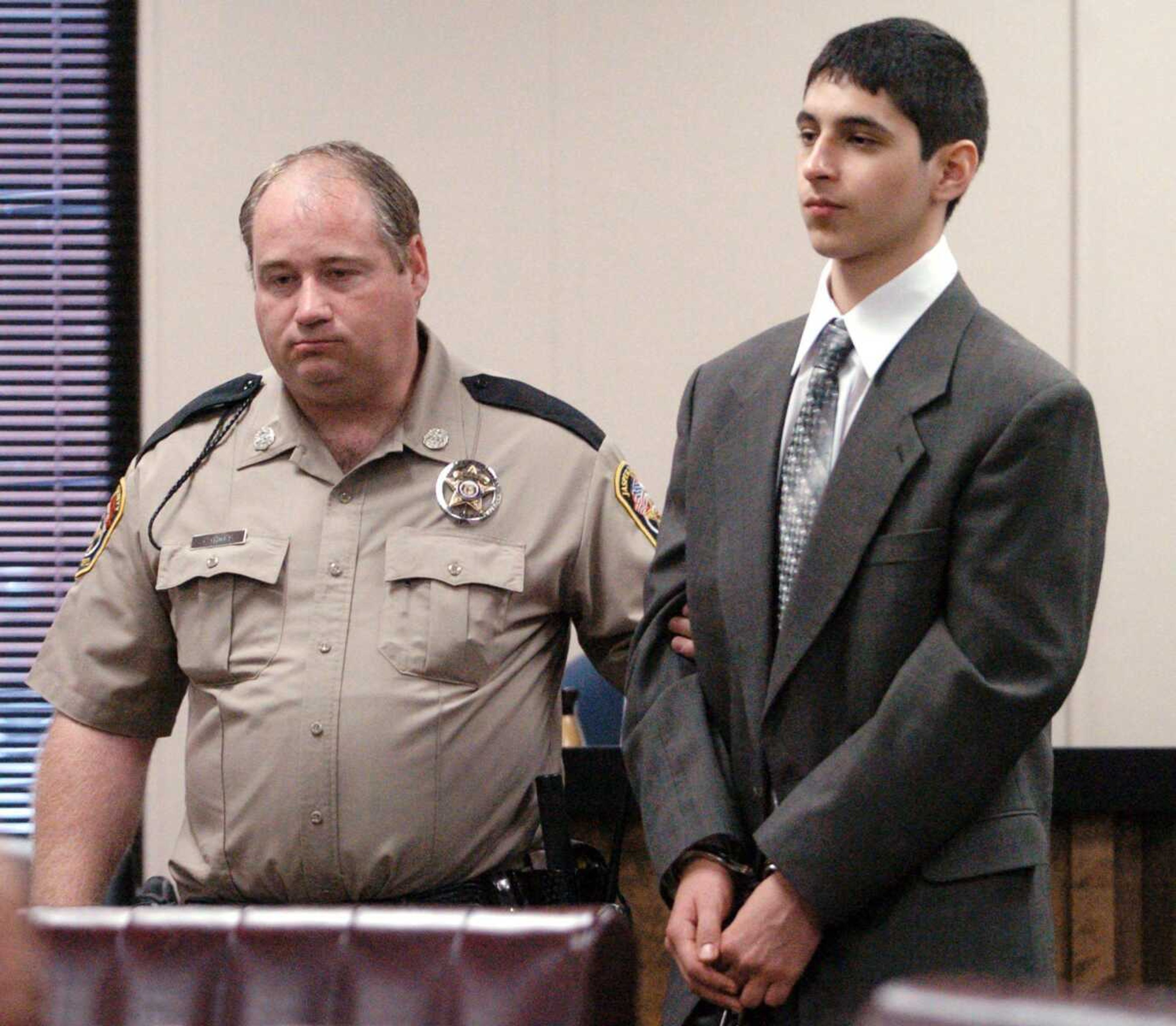 Thomas White, right, of Joplin, is escorted out of the Joplin Courts Building by a Jasper County deputy Friday after White was sentenced to three concurrent 10-year terms in a school-gun case. (T. ROB BROWN ~ Associated Press)