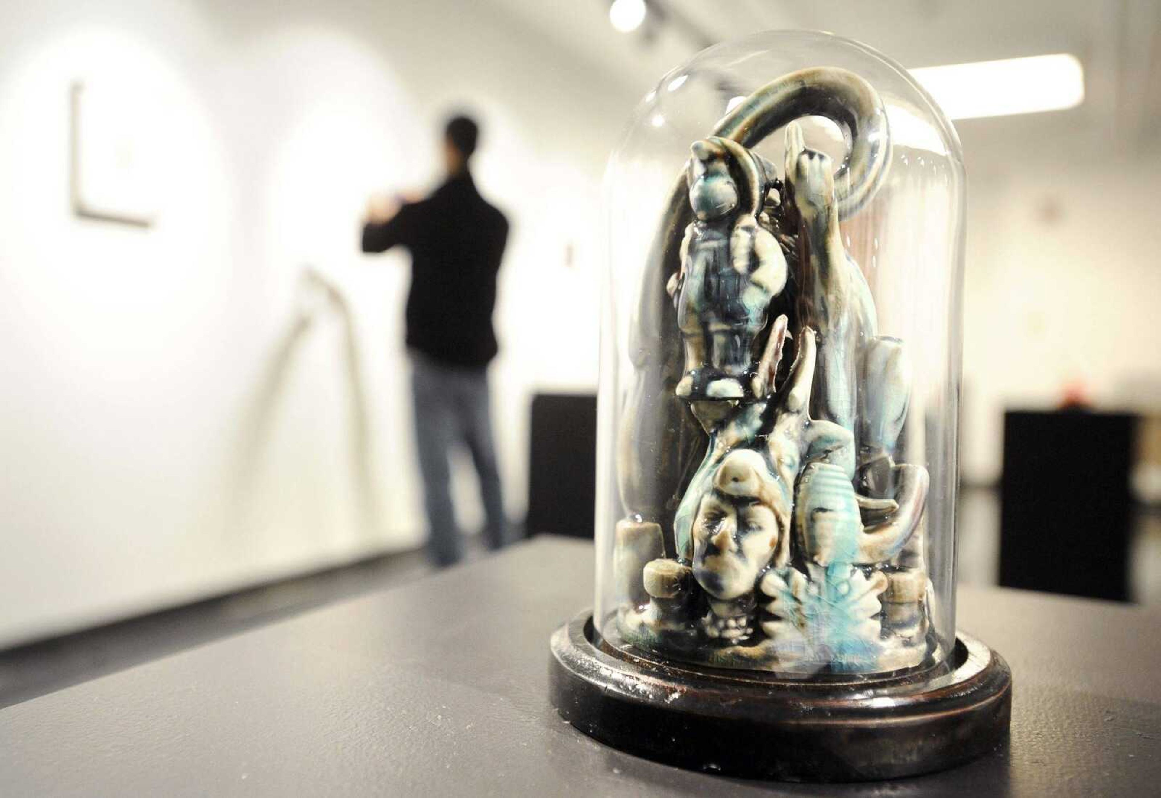 A piece by Craig Clifford sits in the foreground Tuesday as Benjie Heu takes photos of the artwork in the background in the art gallery of the seminary building of Southeast Missouri State University's River Campus. (Laura Simon)