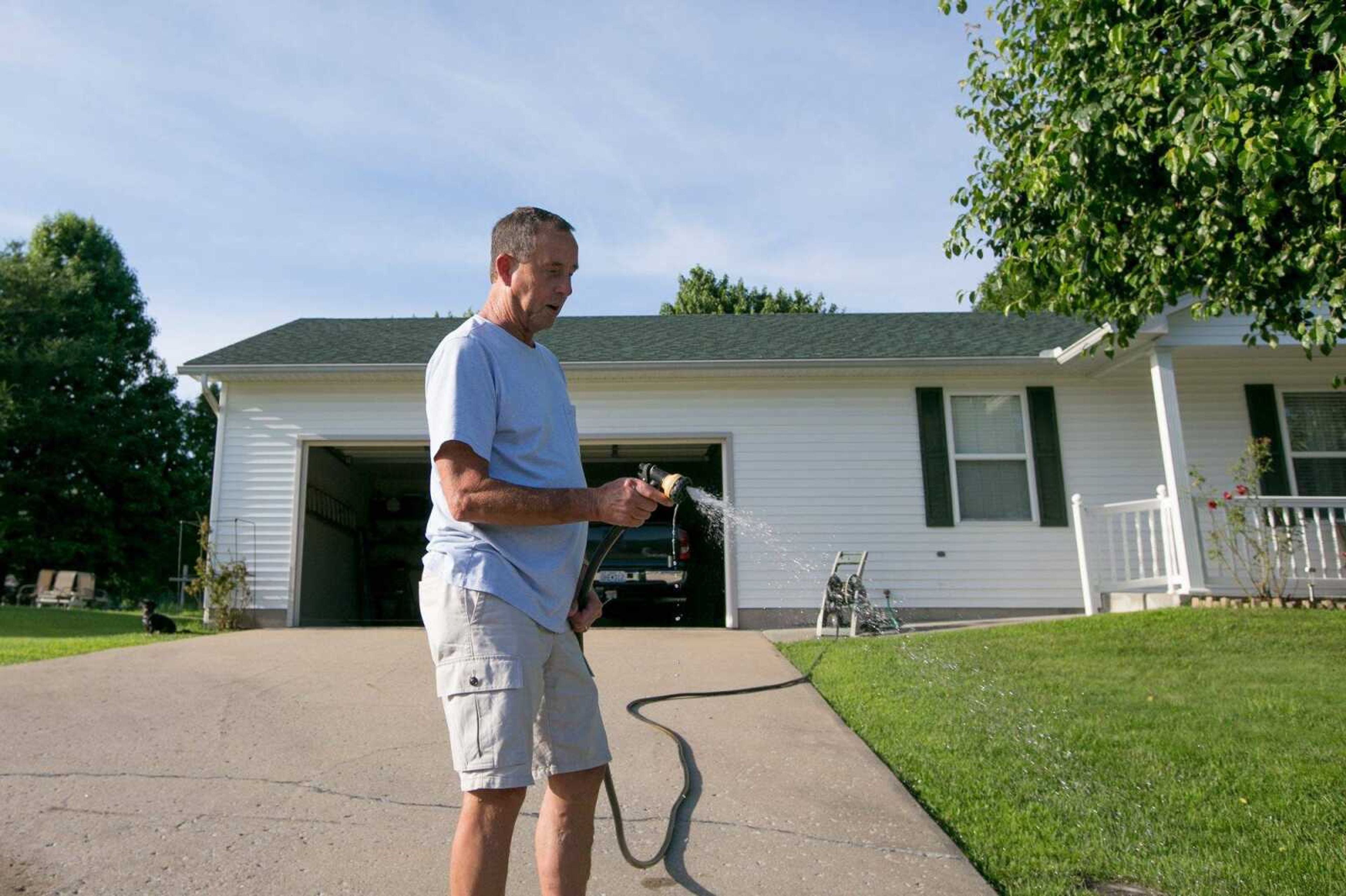 David Lane uses a hose to water a bed of flowers in the front yard of his Hillcrest Manor home June 8 in Cape Girardeau.