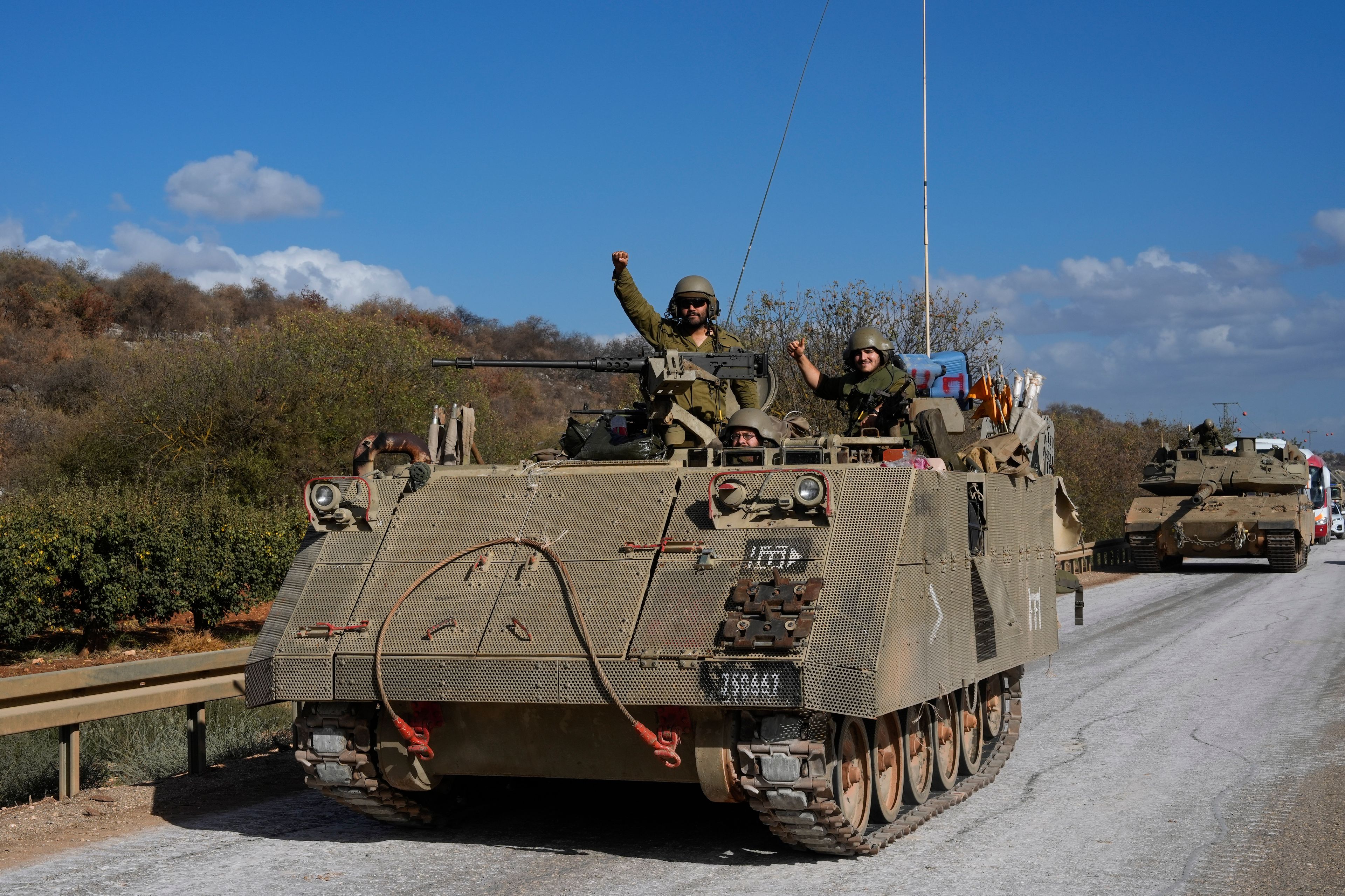 Israeli soldiers raise their fists from a moving APC in northern Israel near the Israel-Lebanon border, Tuesday, Oct. 1, 2024. (AP Photo/Baz Ratner)