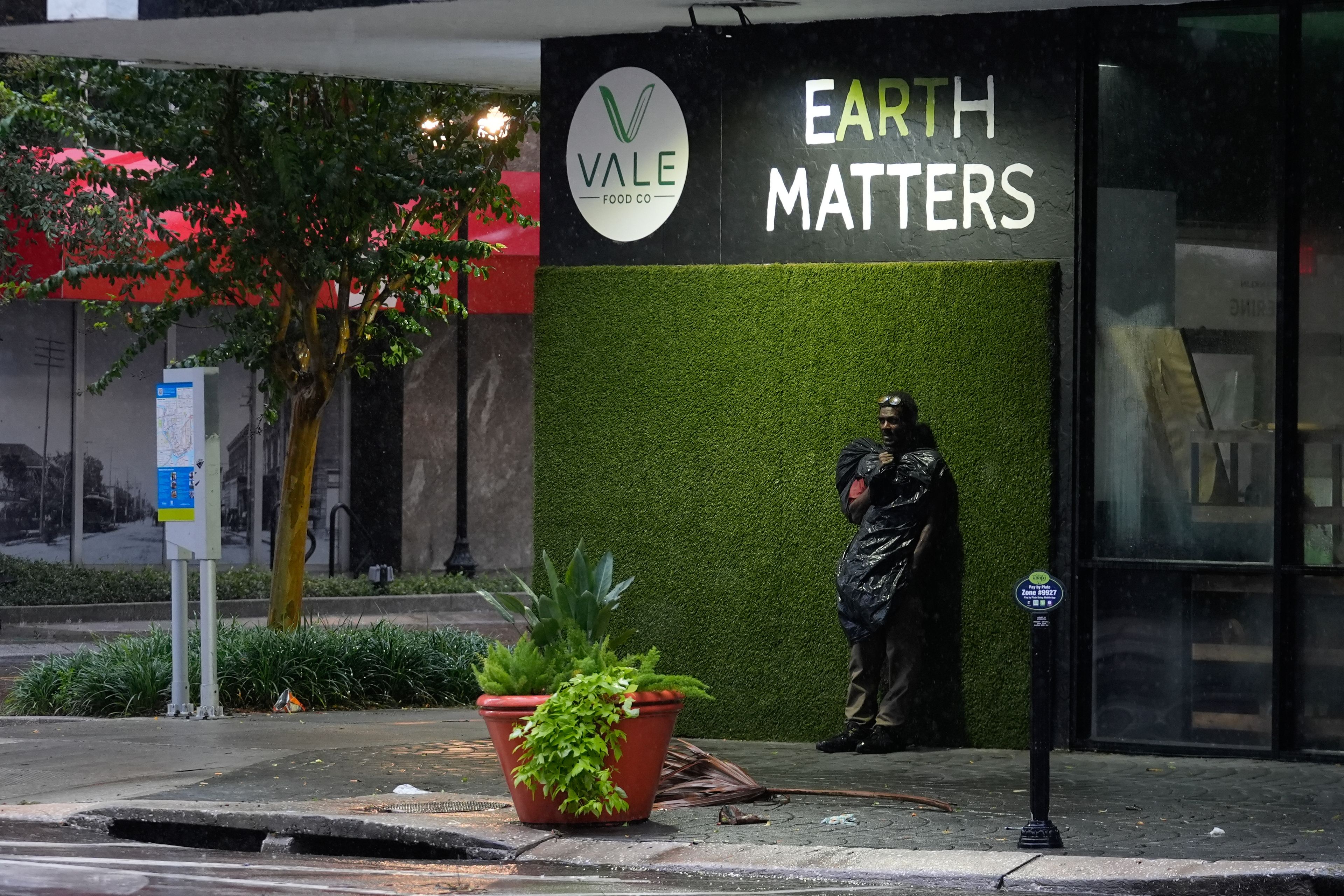 Melvin Lee HIcks, who is homeless, wears a trash bag to protect against wind-driven rain, as he stands on a deserted street in downtown Tampa, Fla., during the approach of Hurricane Milton, Wednesday, Oct. 9, 2024. (AP Photo/Rebecca Blackwell)