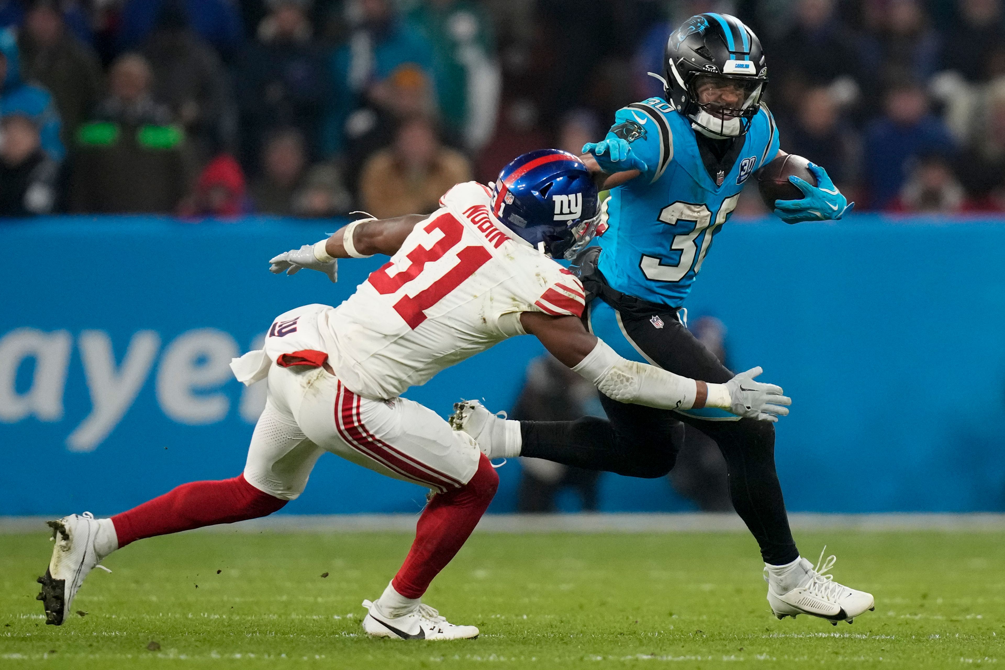 Carolina Panthers running back Chuba Hubbard run past ffNew York Giants safety Tyler Nubin during the second half of an NFL football game, Sunday, Nov. 10, 2024, in Munich, Germany. (AP Photo/Matthias Schrader)