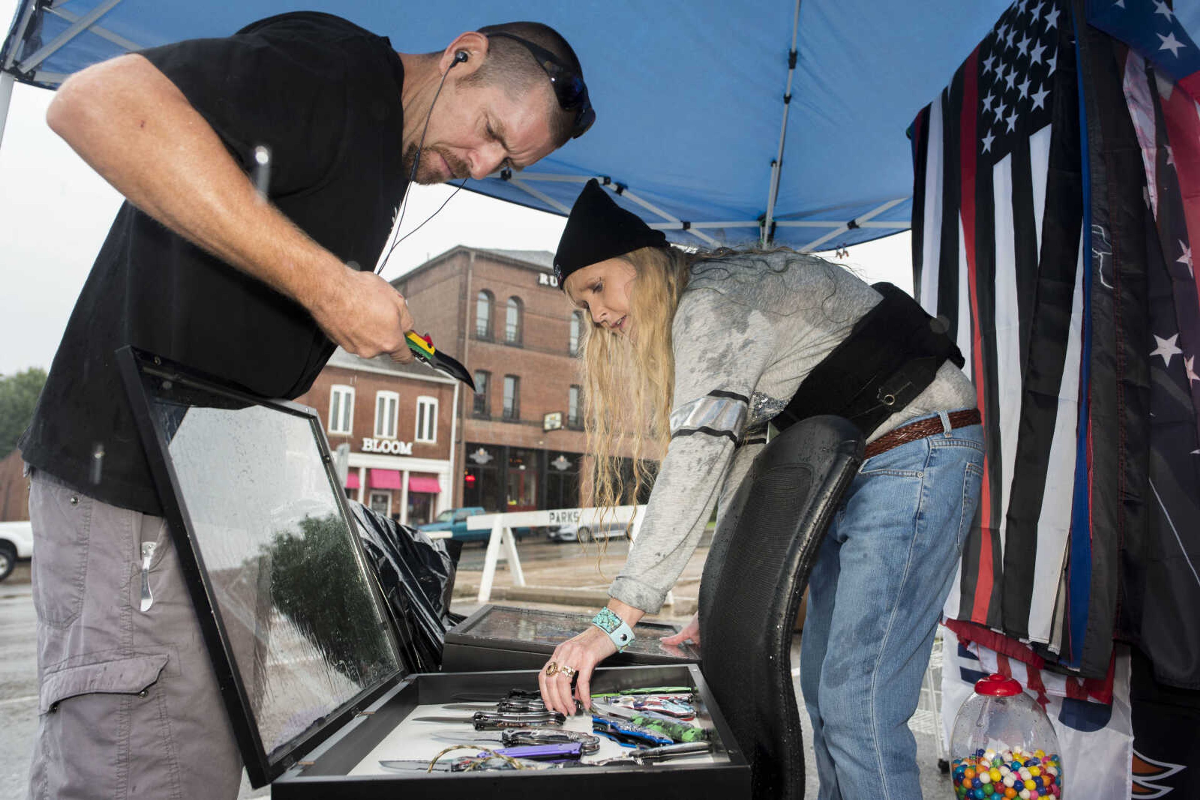 Poplar Bluff vendor Jennifer House, center right, shows a selection of knives to her final customer of the day, Cape Girardeau resident Nate Malone, left, while packing up her stand with Gary House (not pictured) on Sunday, Oct. 6, 2019, at the Cape Girardeau Downtown Tailgate Flea Market. The Houses were two of the last vendors open for business after afternoon rains caused an early closure of the market.