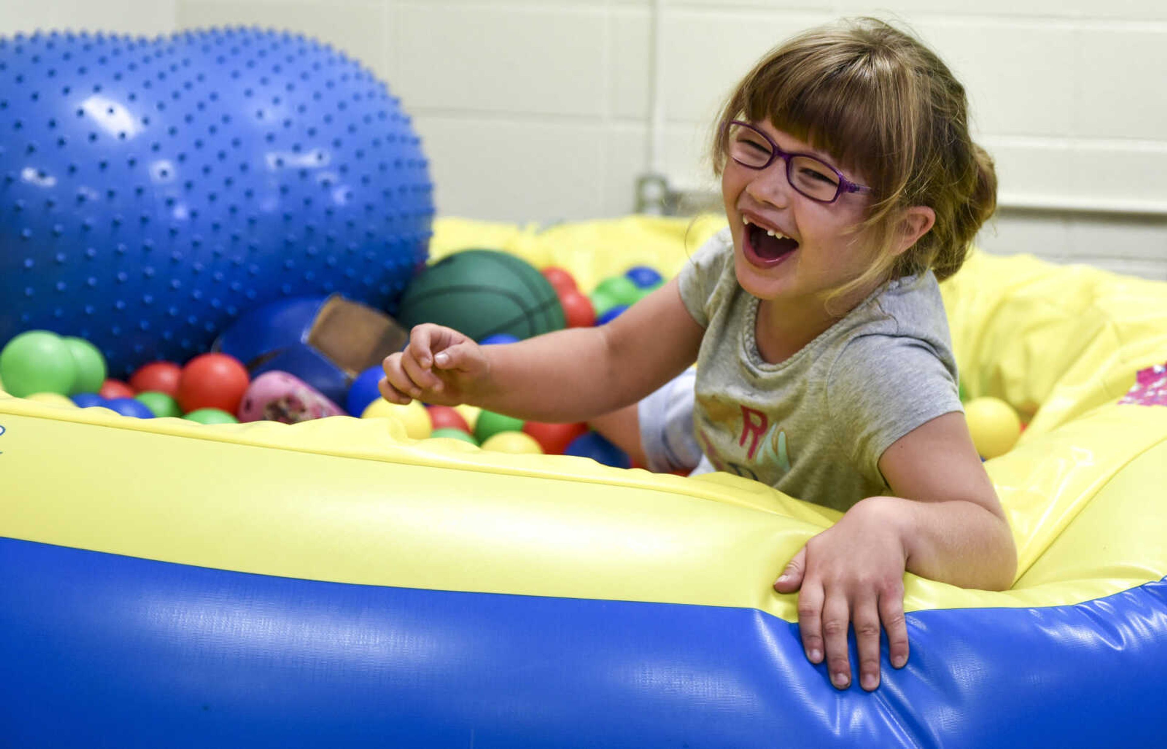 Lindyn Davenport, 6, laughs after jumping into a ball pit as part of her physical therapy at Woodland Elementary School Tuesday, June 5, 2018 in Marble Hill.