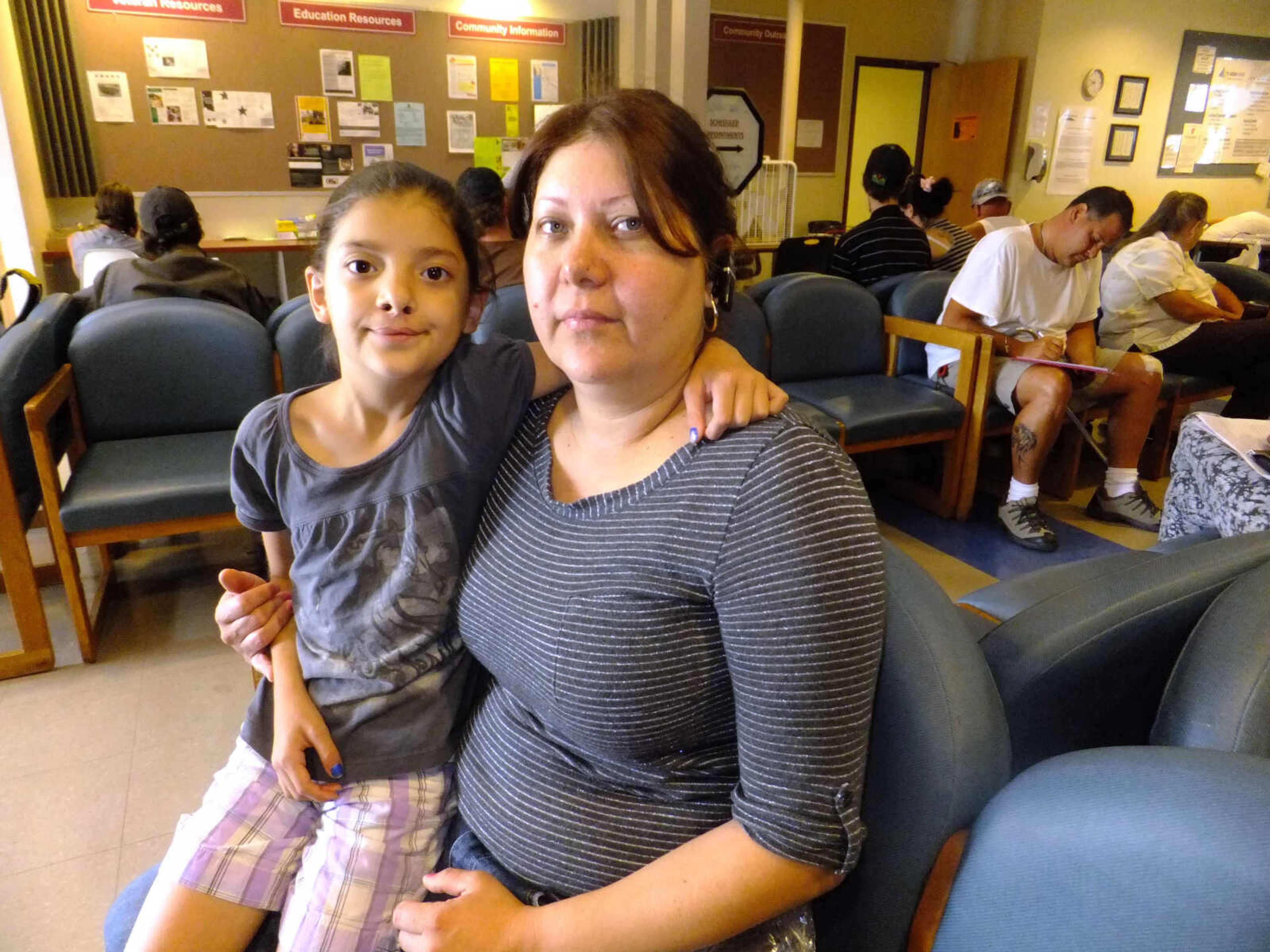 This photo taken July 16, 2012 shows Claudia Pedroza, 39, and her eight-year-old daughter Karla Osorio at the Jefferson Action Center in Lakewood, Colo. Pedroza moved to the Denver suburbs five years ago with her husband and four children in hopes of a more comfortable suburban life. But Pedroza's family struggles to make ends meet and she was waiting with her   on Monday, July 16, 2012, to apply for help with food, toiletries and seek a new frying pan. (AP Photo/Kristen Wyatt)