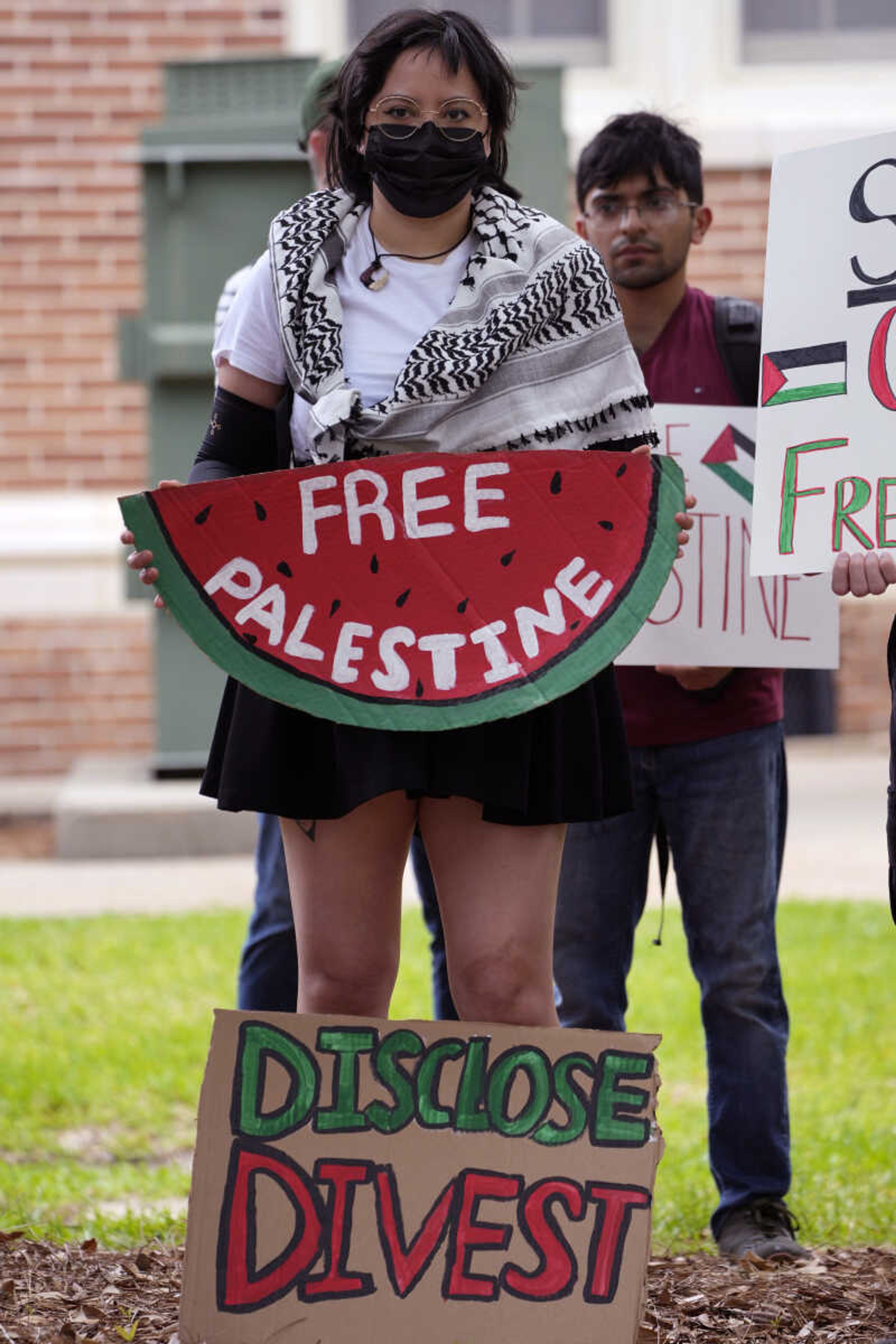 A protester holds her Pro-Palestinian signs protesting the Israel Hamas war in Gaza, and encouraging the University of Southern Mississippi to stop doing business with Israel or companies supporting the war in Gaza, during an hour-long silent protest on the school's campus, Tuesday, May 7, 2024, in Hattiesburg, Miss. The group of almost 50 demonstrators drew no counter protesters or hecklers. (AP Photo/Rogelio V. Solis)