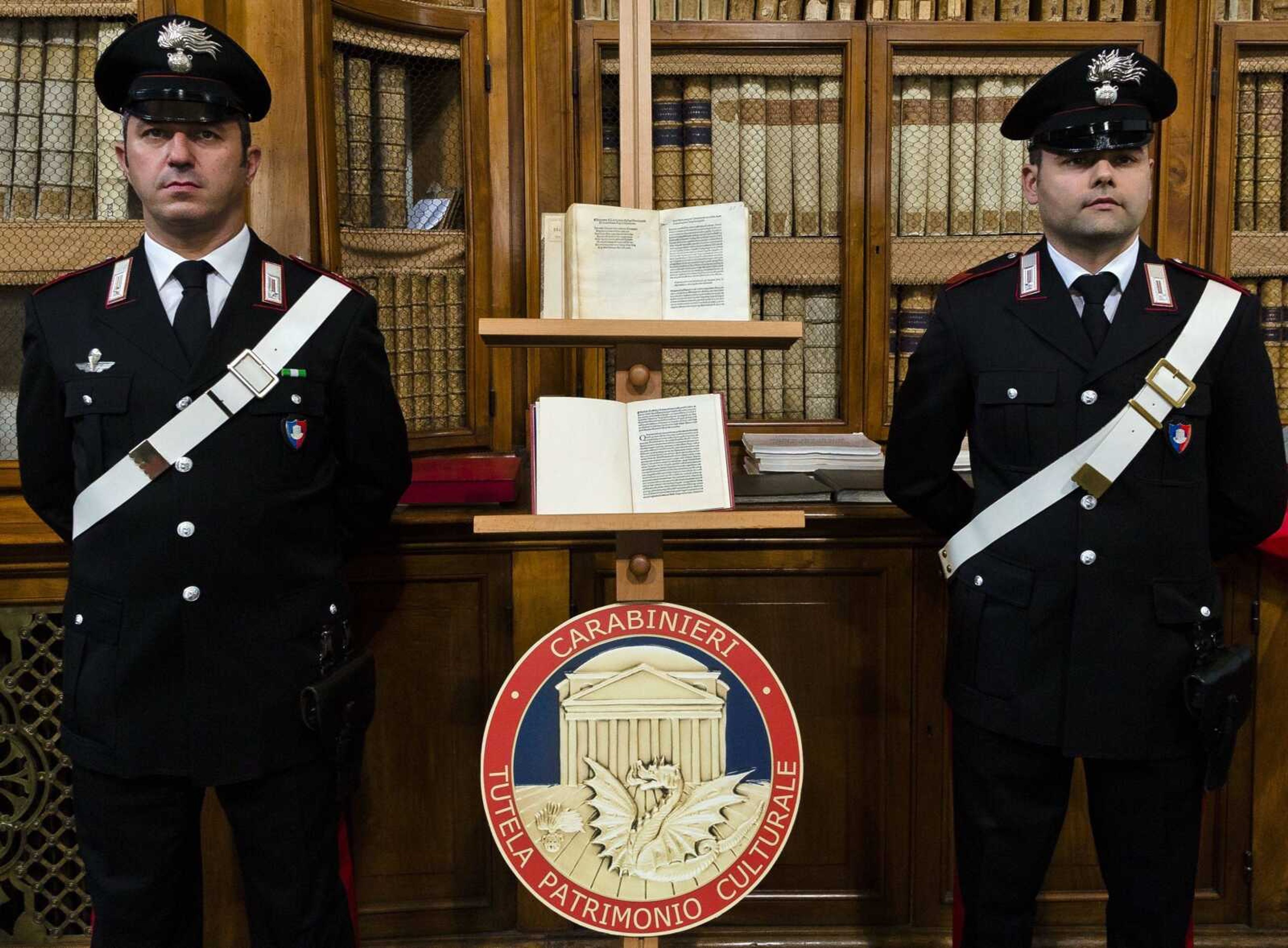 Italian Carabinieri officers stand by a reprinted copy of Christopher Columbus original letter written in 1493 about the discovery of the New World, on the stand below, and a fake of the reprinted copy, above, during a news conference Wednesday in Rome. The United States has returned to Italy a letter written by Christopher Columbus that was stolen from a Florence library, unwittingly acquired by the Library of Congress and replaced with a forgery no one noticed until a few years ago.