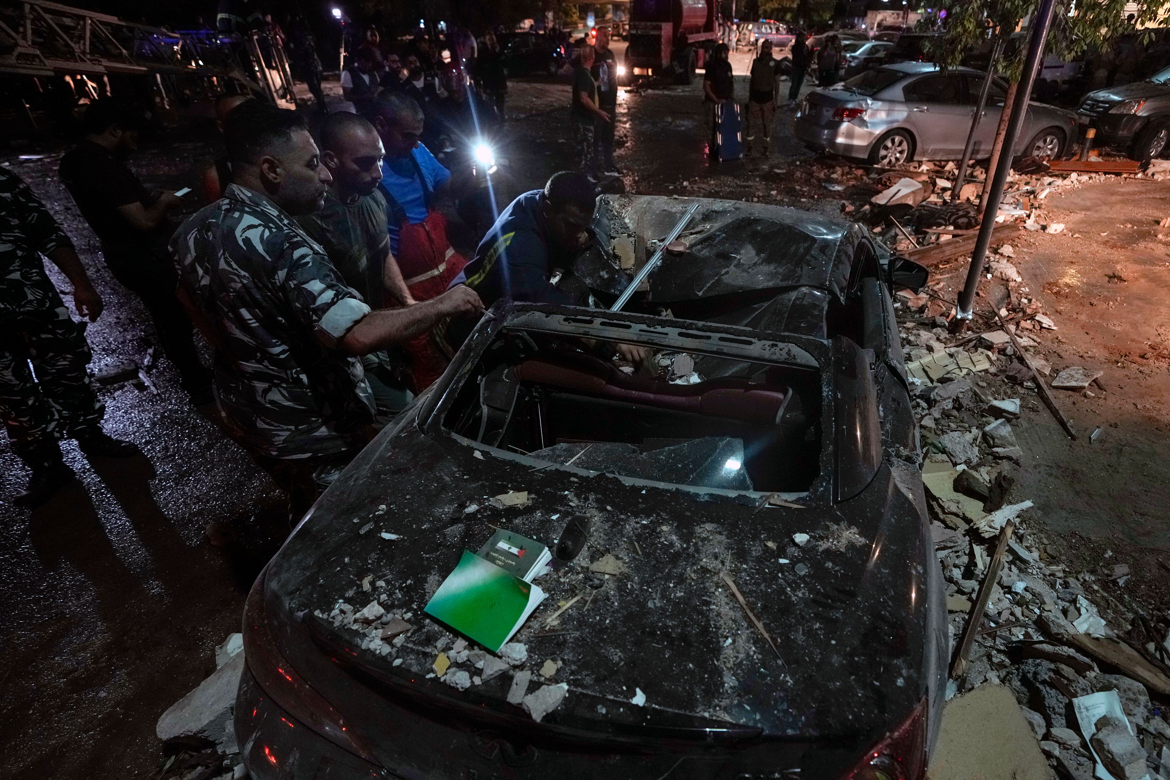 Policemen and civil defense workers inspect a damaged car near a building that was hit in an Israeli airstrike, in Beirut, Lebanon, early Monday, Sept. 30, 2024. (AP Photo/Bilal Hussein)