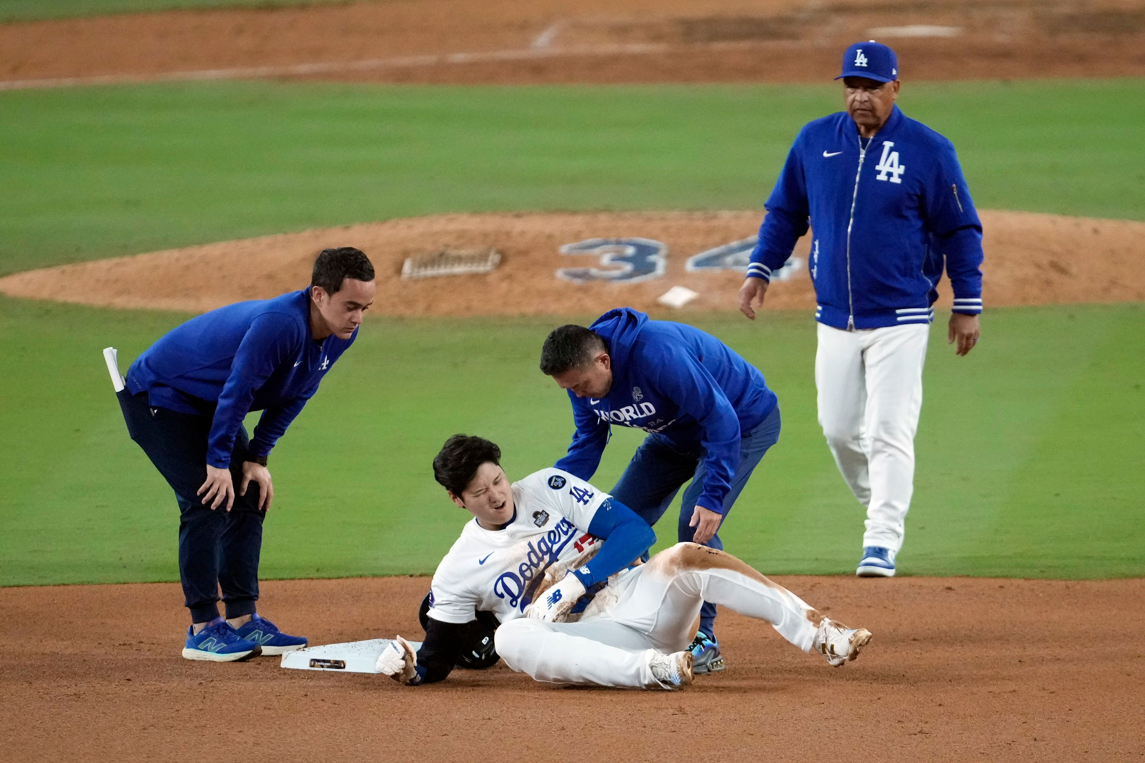 Los Angeles Dodgers' Shohei Ohtani, center, reacts after being injured while trying to steal second base against the New York Yankees during the seventh inning in Game 2 of the baseball World Series, Saturday, Oct. 26, 2024, in Los Angeles. (AP Photo/Julio Cortez)