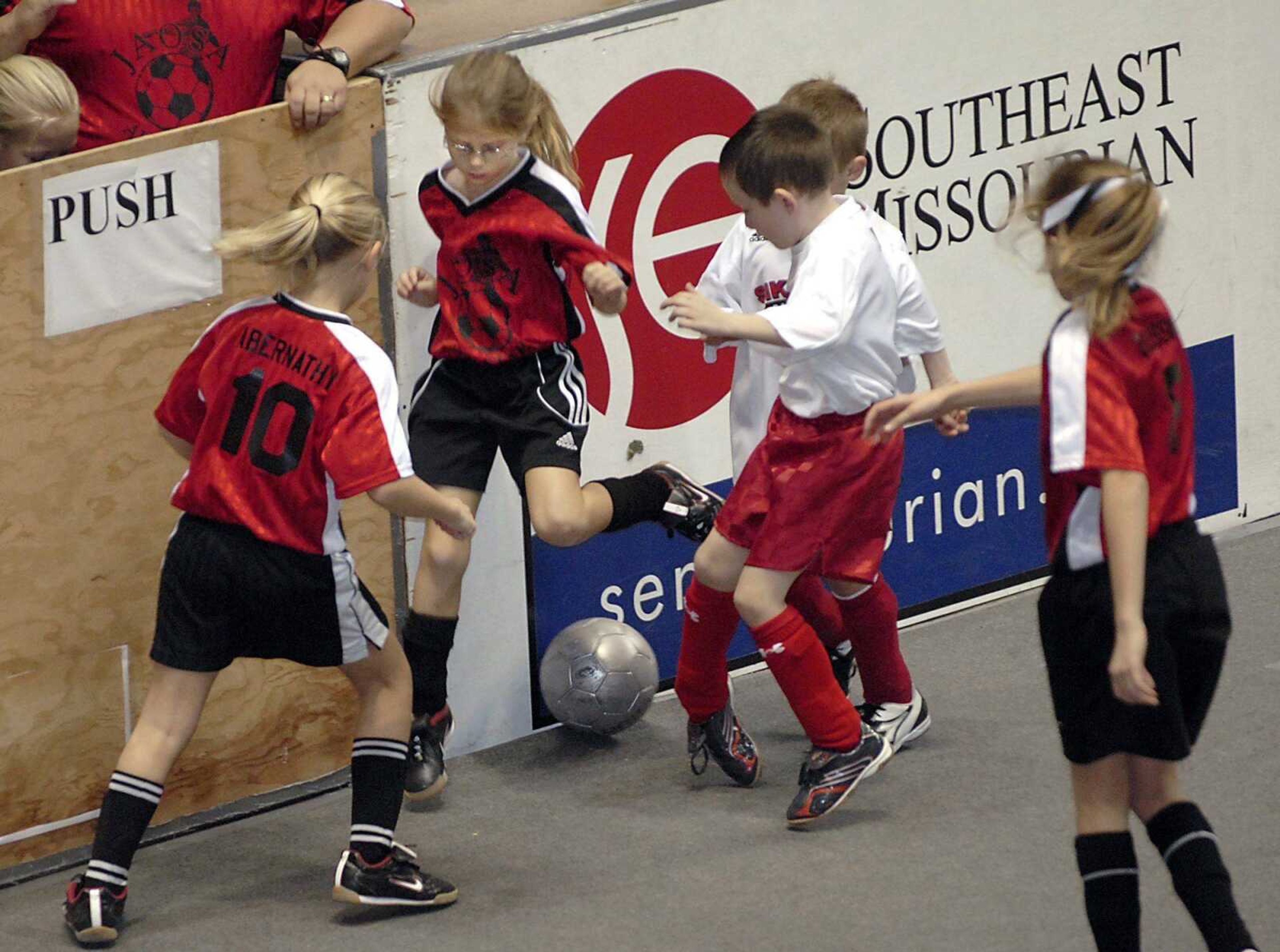 Brittney Hawk attempted to kick the ball to her Jackson Redhots teammates, Megan Abernathy, left, and Addie Beussink, and away from Sikeston Shield's Bryce Miller and Layne Robinson, behind him, in the under-8 co-ed division at the 14th annual Saint Francis Indoor Soccer Invitational on Sunday at the Show Me Center. The Redhots won the game 5-3. (Fred Lynch)