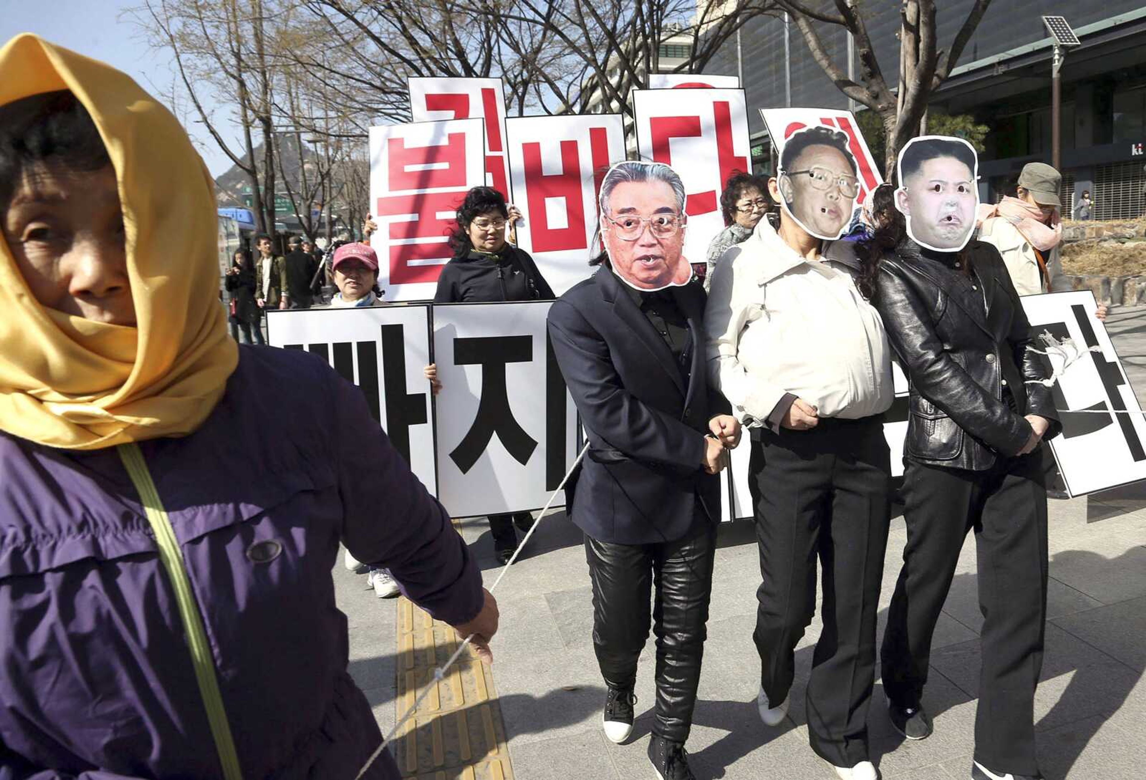 A North Korean defector pulls South Korean activists wearing masks of North Korean leader Kim Jong Un, right, and the late North Korean leader Kim Jong Il with their hands tied with a rope during a rally against North Korea on Sunday in Seoul, South Korea.<br>Yonhap Lee Ji-Eun<br>Associated Press