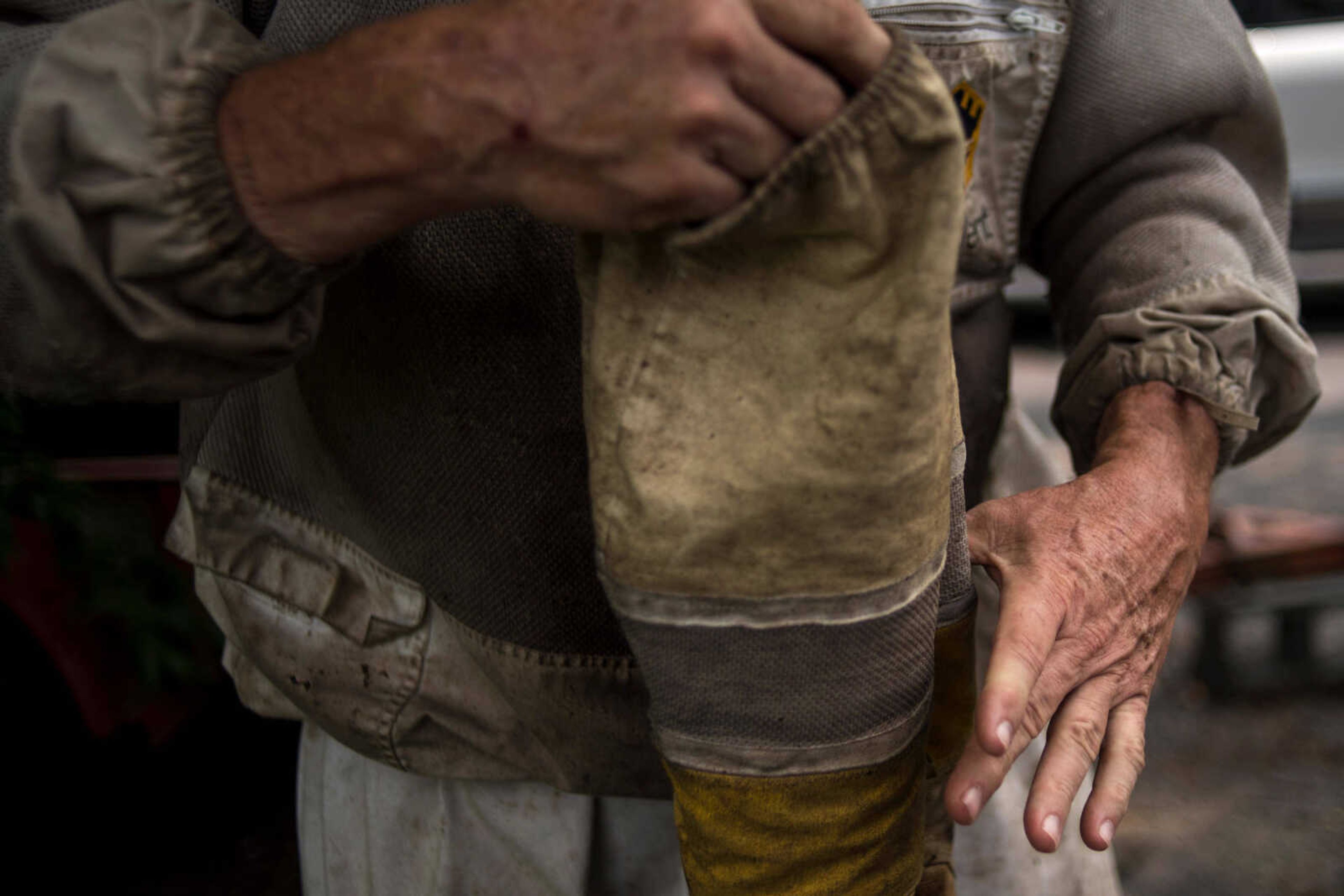 Paul Koeper removes protective gloves after inspecting his bees at one of Koeper's hives in Jackson.