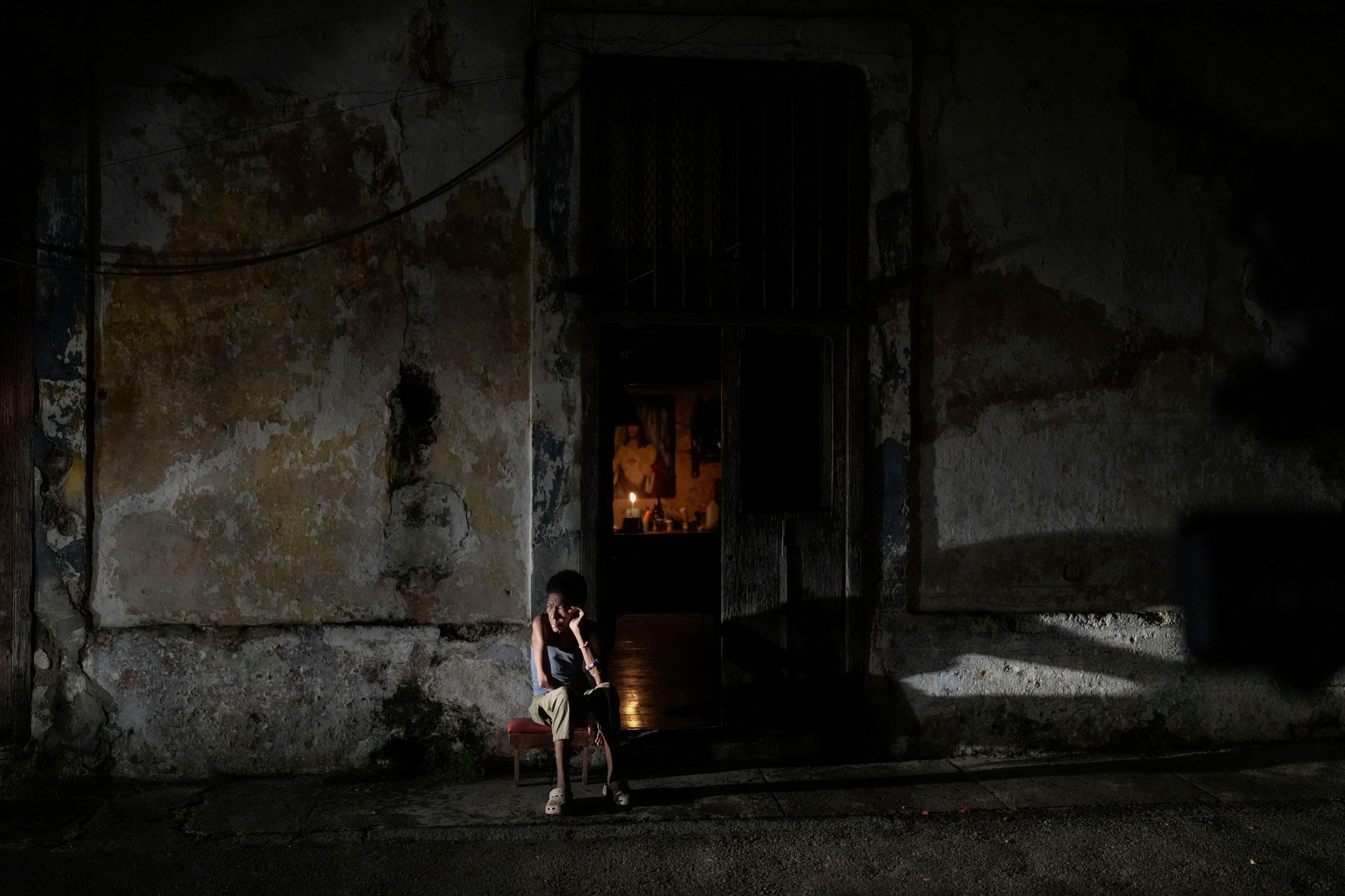 A resident sits while passing time during a blackout following the failure of a major power plant in Havana, Cuba, Saturday, Oct. 19, 2024. (AP Photo/Ramon Espinosa)