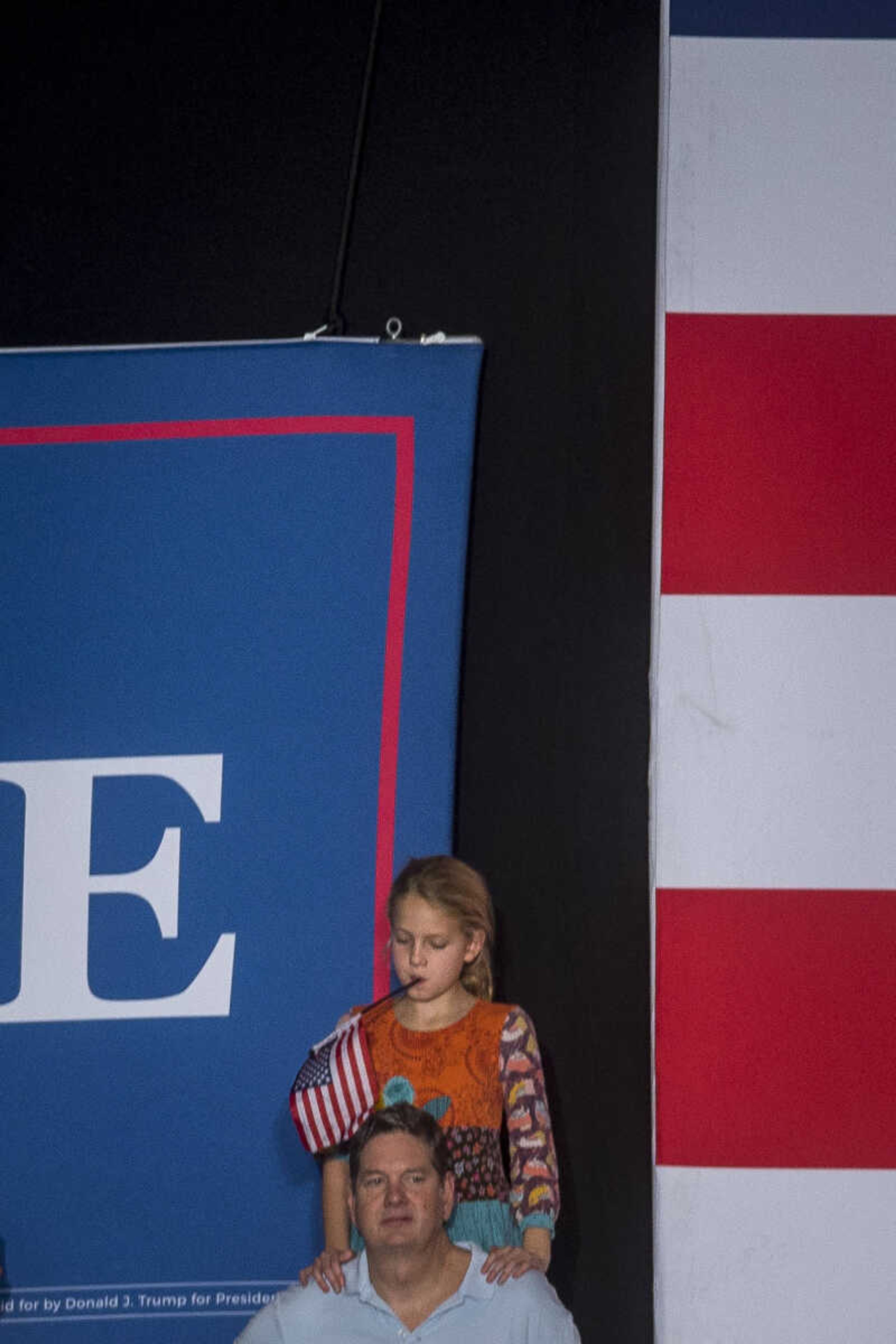 A young girl plays with an American flag during a rally for President Trump at the Show Me Center Monday.