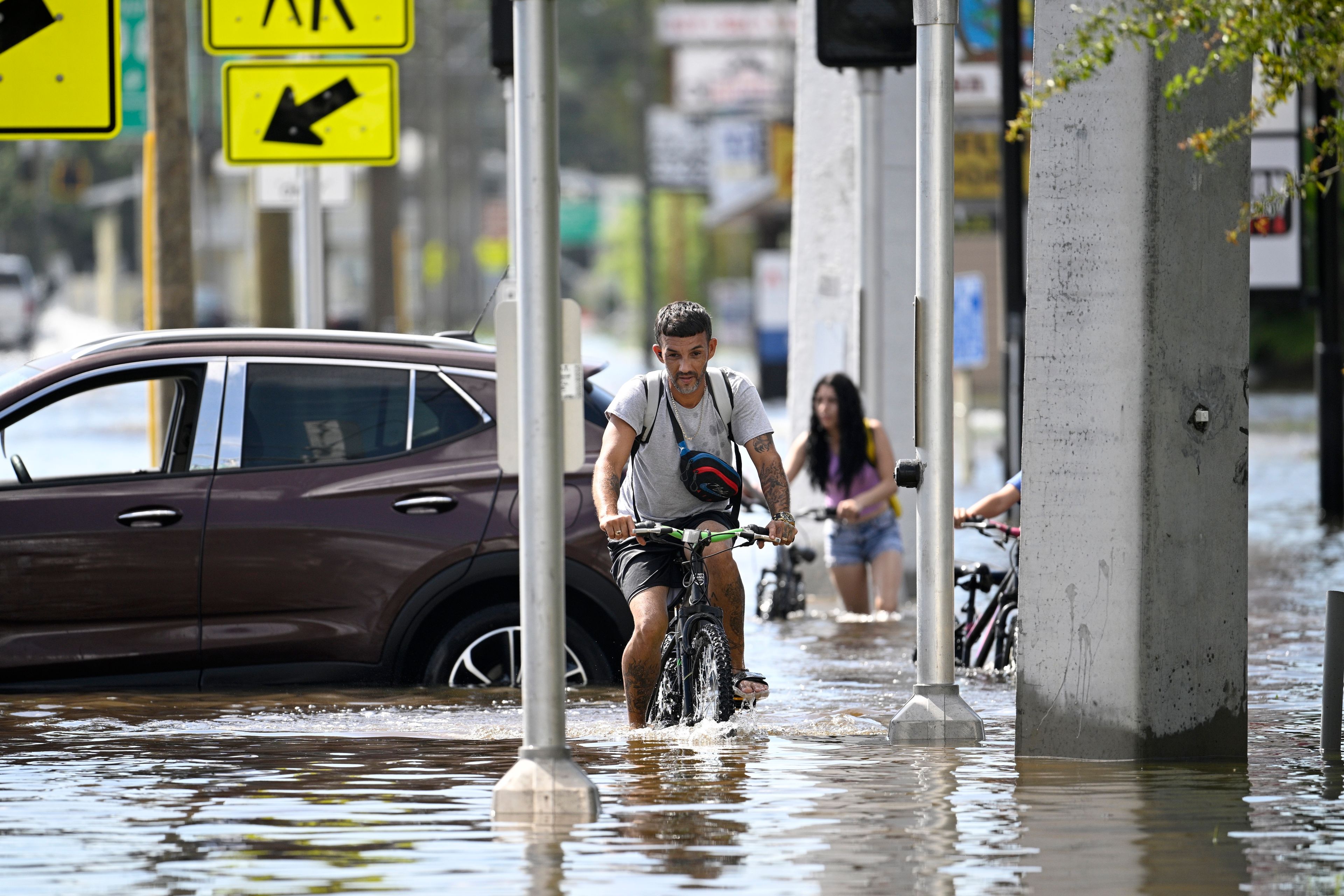 FILE - Mica Martell, left, and his niece and nephews ride bicycles through a flooded neighborhood, Sept. 27, 2024, in Crystal River, Fla. (AP Photo/Phelan M. Ebenhack, File)