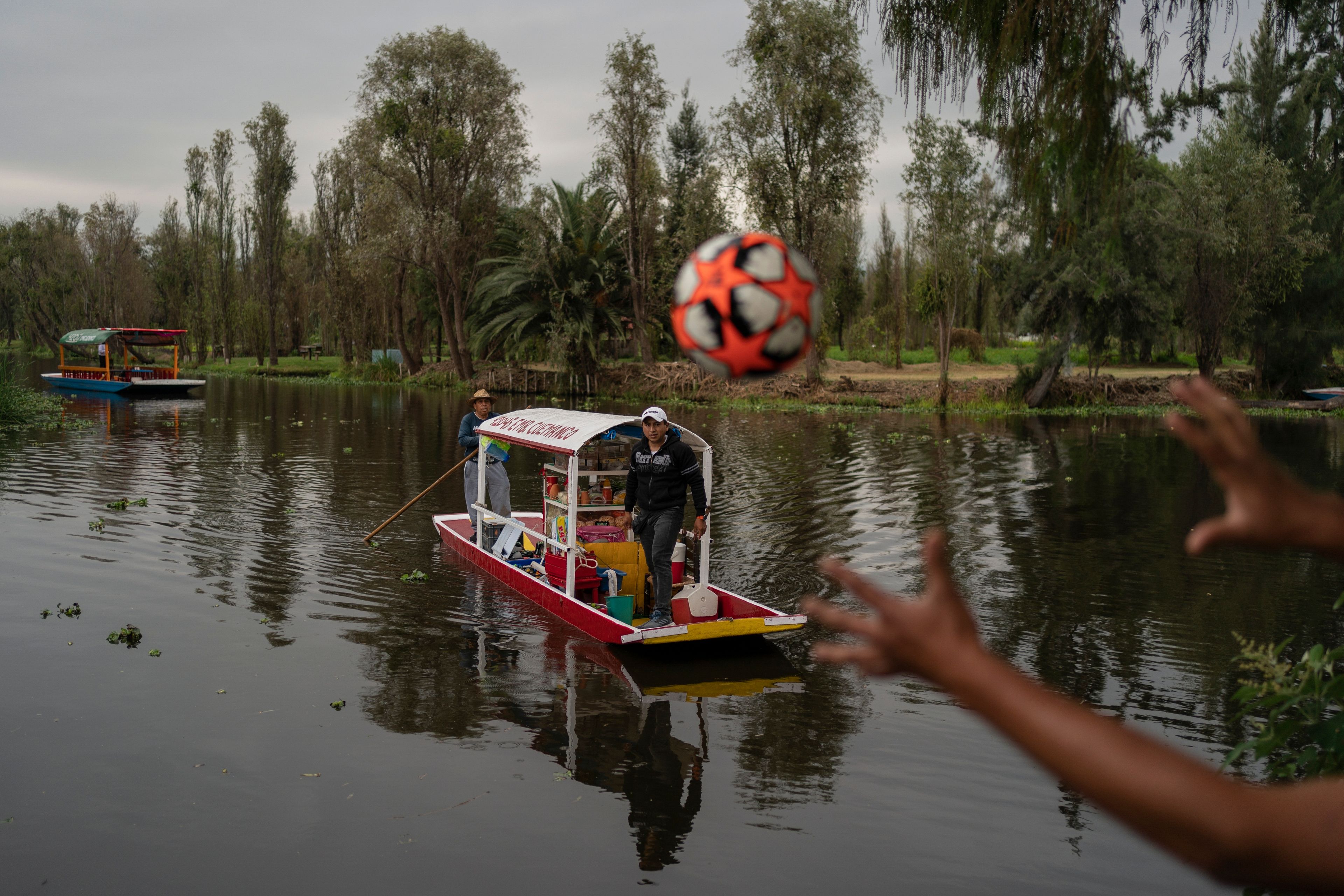 A man on a traditional canoe launches a soccer ball that fell into the lake in the Xochimilco borough of Mexico City, Sunday, Oct. 20, 2024. (AP Photo/Felix Marquez)