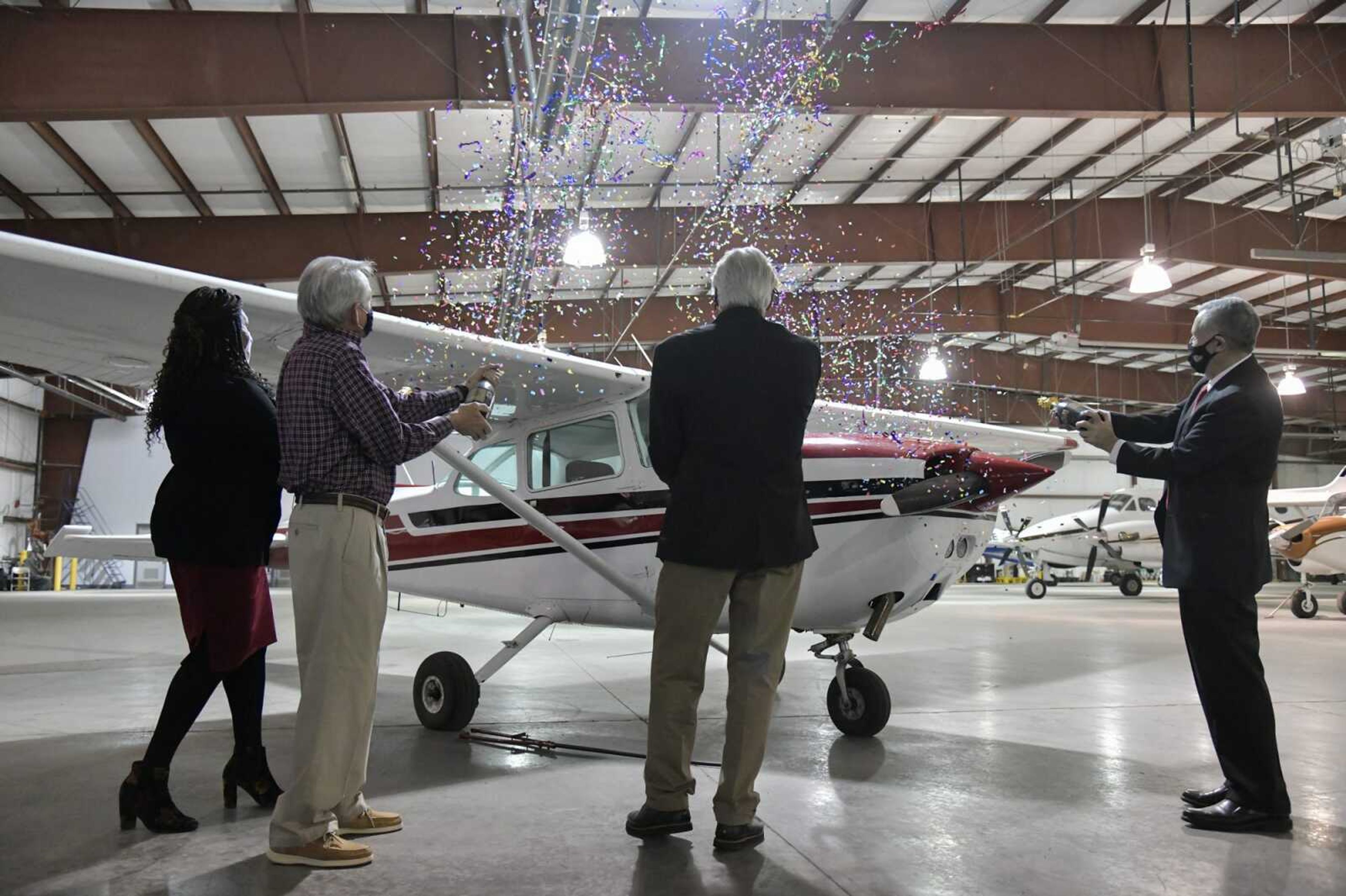 (From left) Katrina Amos and Bruce Loy of the airport, Mark Taylor of U.S. Aviation Group and SEMO president Carlos Vargas release confetti on a Cessna 172 aircraft, the aircraft the school plans to use for instruction, during the announcement of the new Southeast Missouri State University Professional Pilot Bachelor of Science degree program at the Cape Girardeau Regional Airport Dec. 4, 2020.