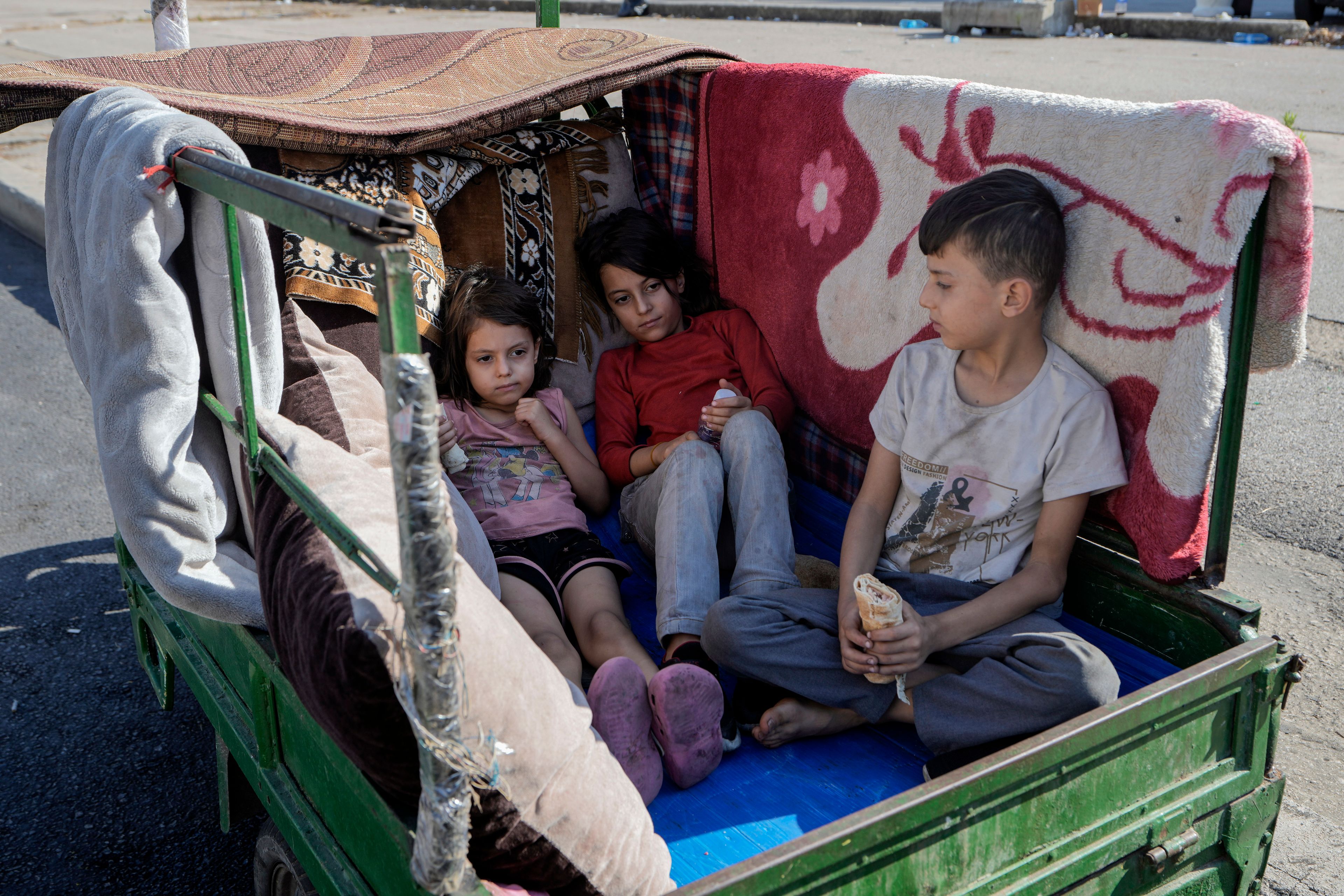 Children sit in a motorcycle cart in Beirut's Martyrs' square after fleeing the Israeli airstrikes in the southern suburbs of Dahiyeh, Sunday, Sept. 29, 2024. (AP Photo/Bilal Hussein)