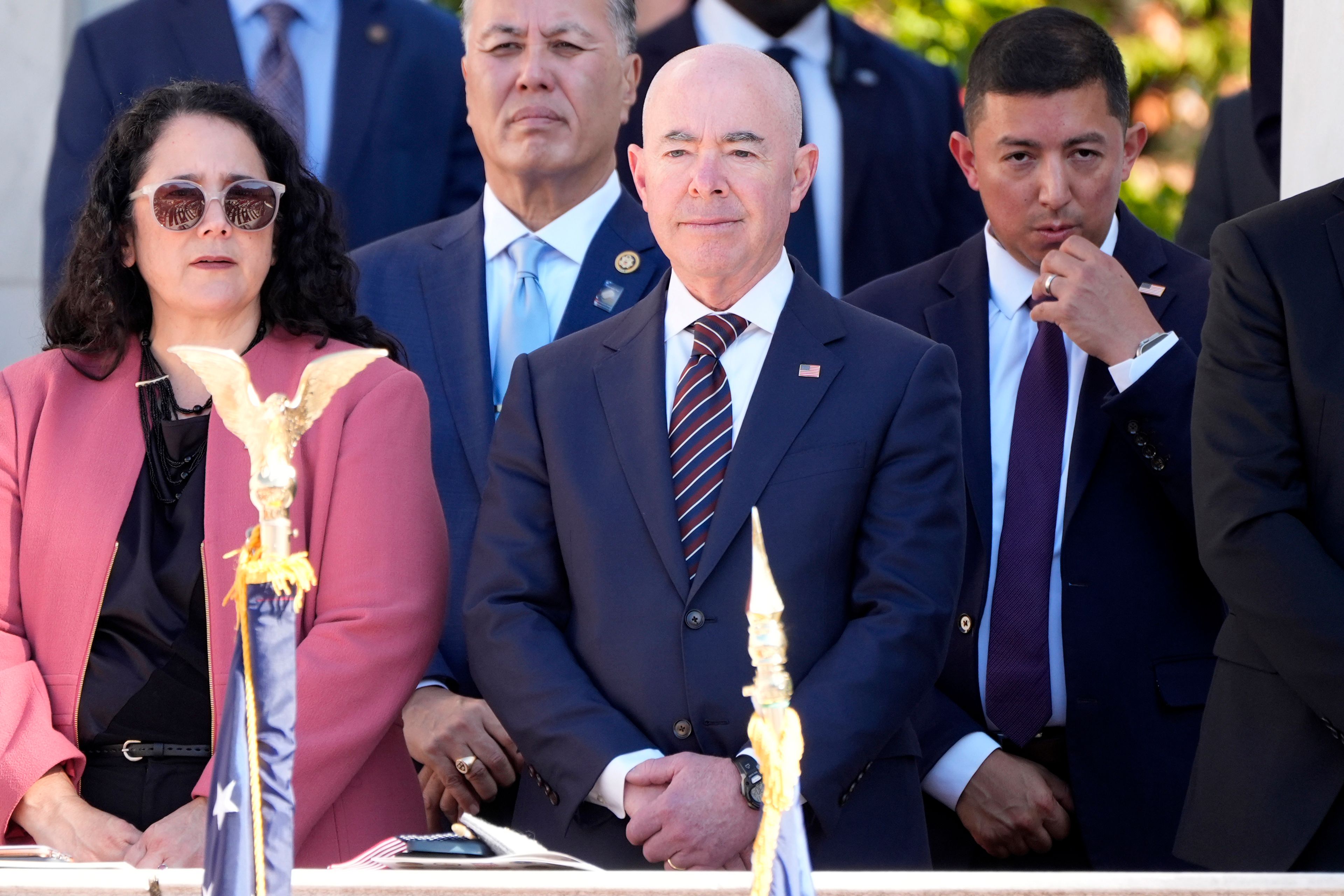 Homeland Security Secretary Alejandro Mayorkas, center, looks on before President Joe Biden speaks at the National Veterans Day Observance at the Memorial Amphitheater at Arlington National Cemetery in Arlington, Va., Monday, Nov. 11, 2024. (AP Photo/Mark Schiefelbein)