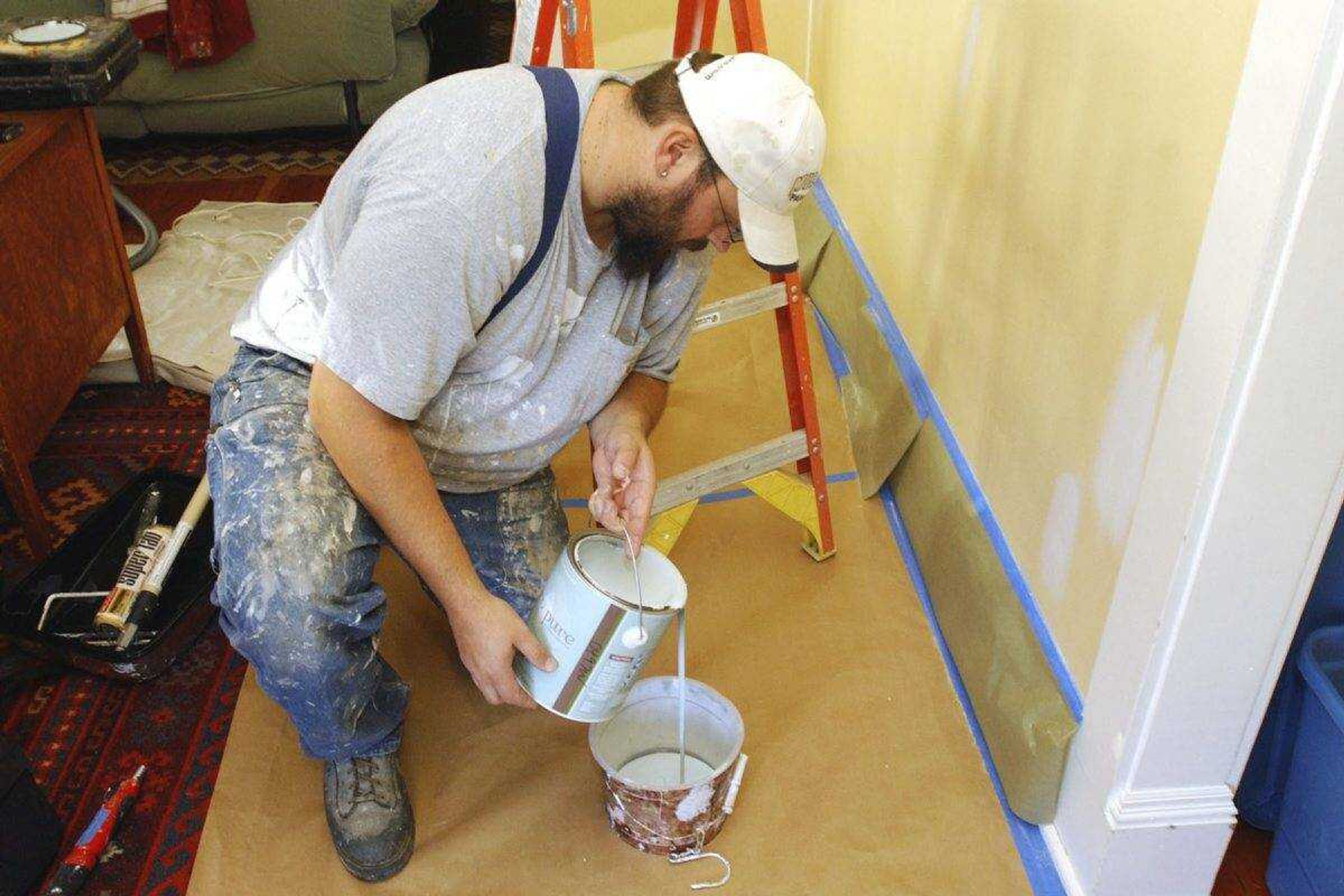 Painting contractor Andrew Lohr pours out the paint into a tray prior to paint his living room Dec. 5, 2008, in Portland, Oregon.