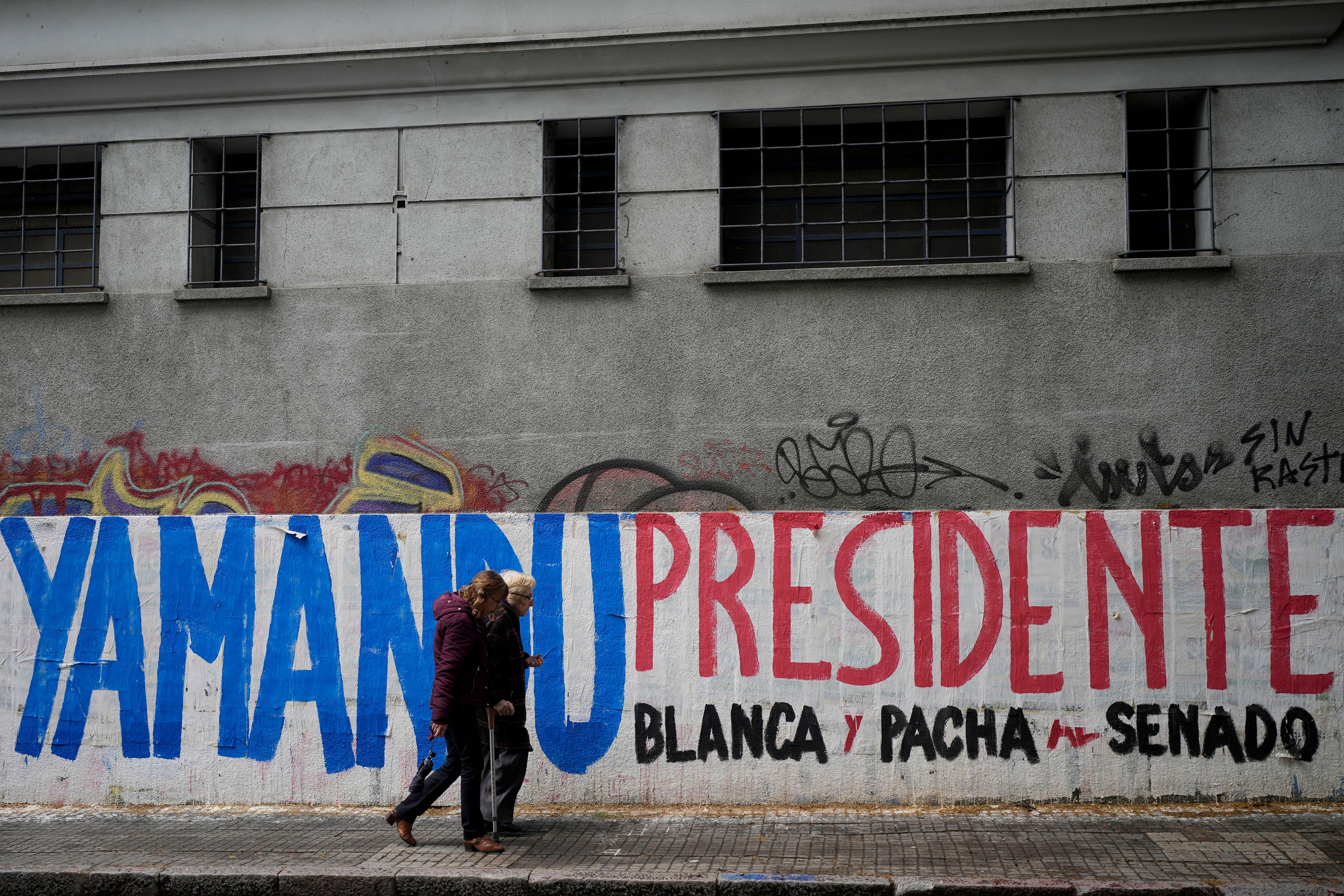 Pedestrians walk past a campaign mural promoting Frente Amplio presidential candidate Yamandu Orsi, ahead of Sunday's upcoming general election, in Montevideo, Uruguay, Friday, Oct. 25, 2024. (AP Photo/Natacha Pisarenko)