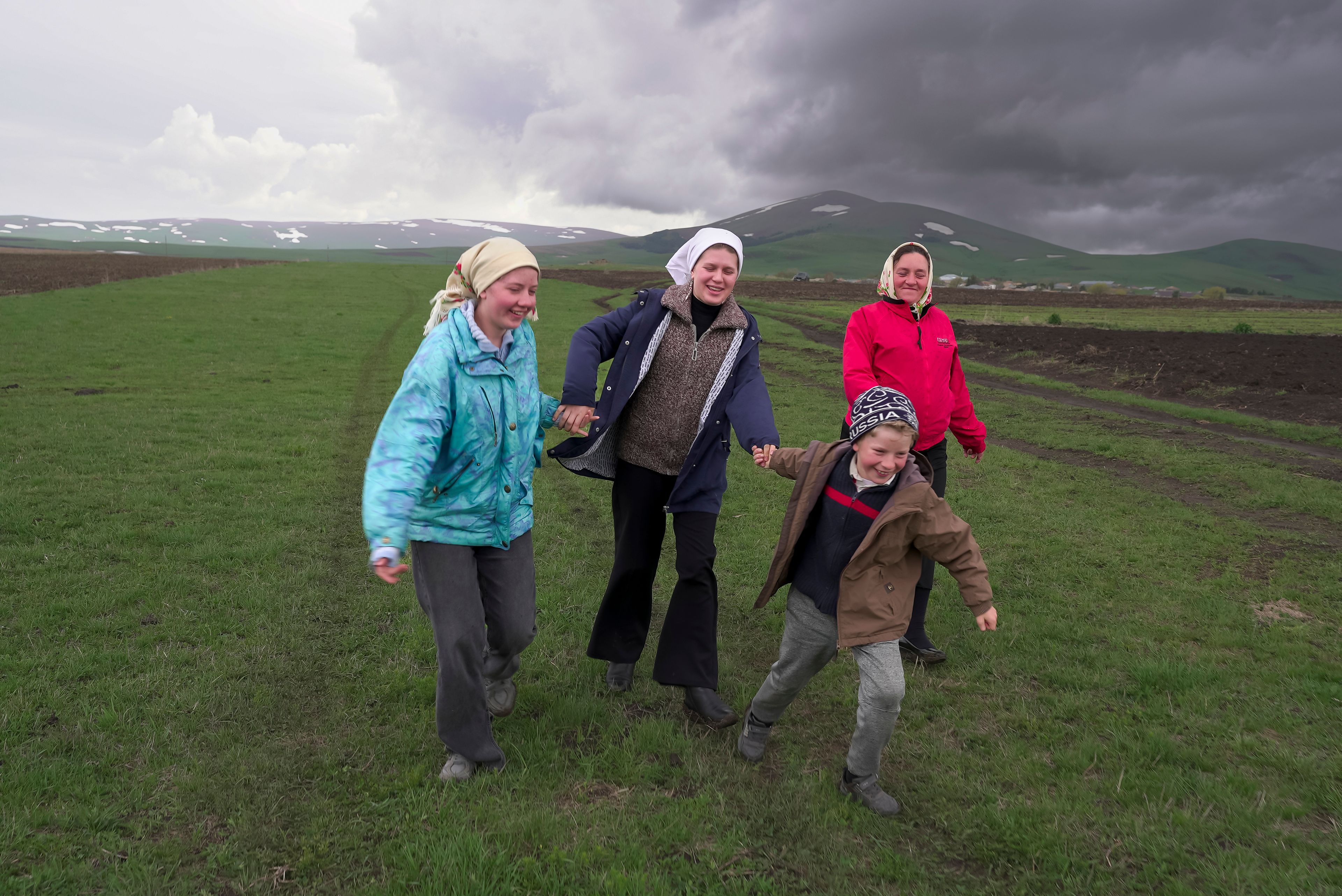 Nina Strukova, Daria Strukova, Ilya Strukov and their mother Svetlana Svetlishcheva walk to a cemetery outside the remote mountain village of Orlovka, Georgia, Saturday, May 5, 2024. (AP Photo/Kostya Manenkov)