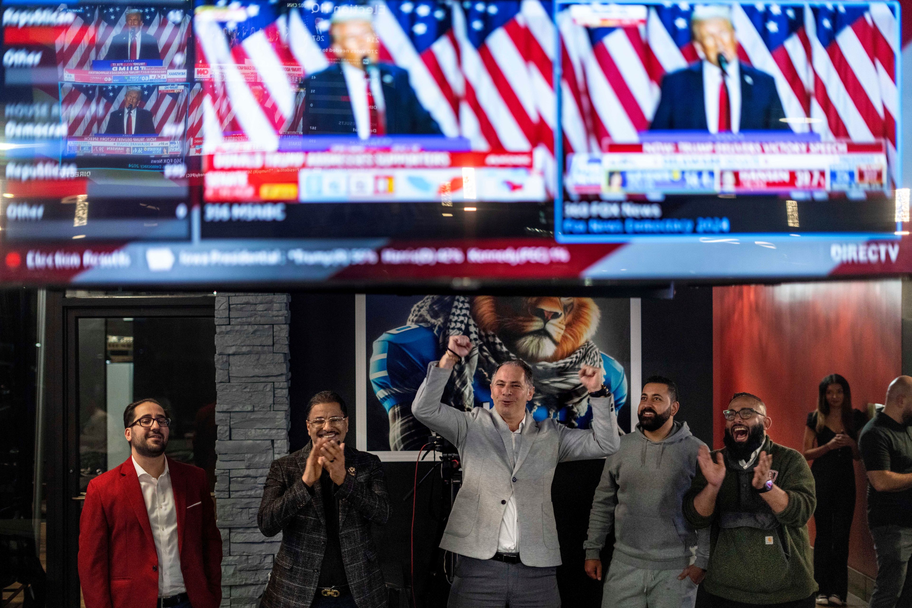 From left, Paul Manni, Sam Alasri, Wasel Yousaf, Waseem Makani and Abrahim Tamimi, cheer as Republican presidential nominee former President Donald Trump's speech is broadcast during an Arab Americans for Trump watch party at the Lava Java Cafe, a hookah lounge, in the early hours of Wednesday, Nov. 6, 2024, in Dearborn, Mich. (AP Photo/David Goldman)