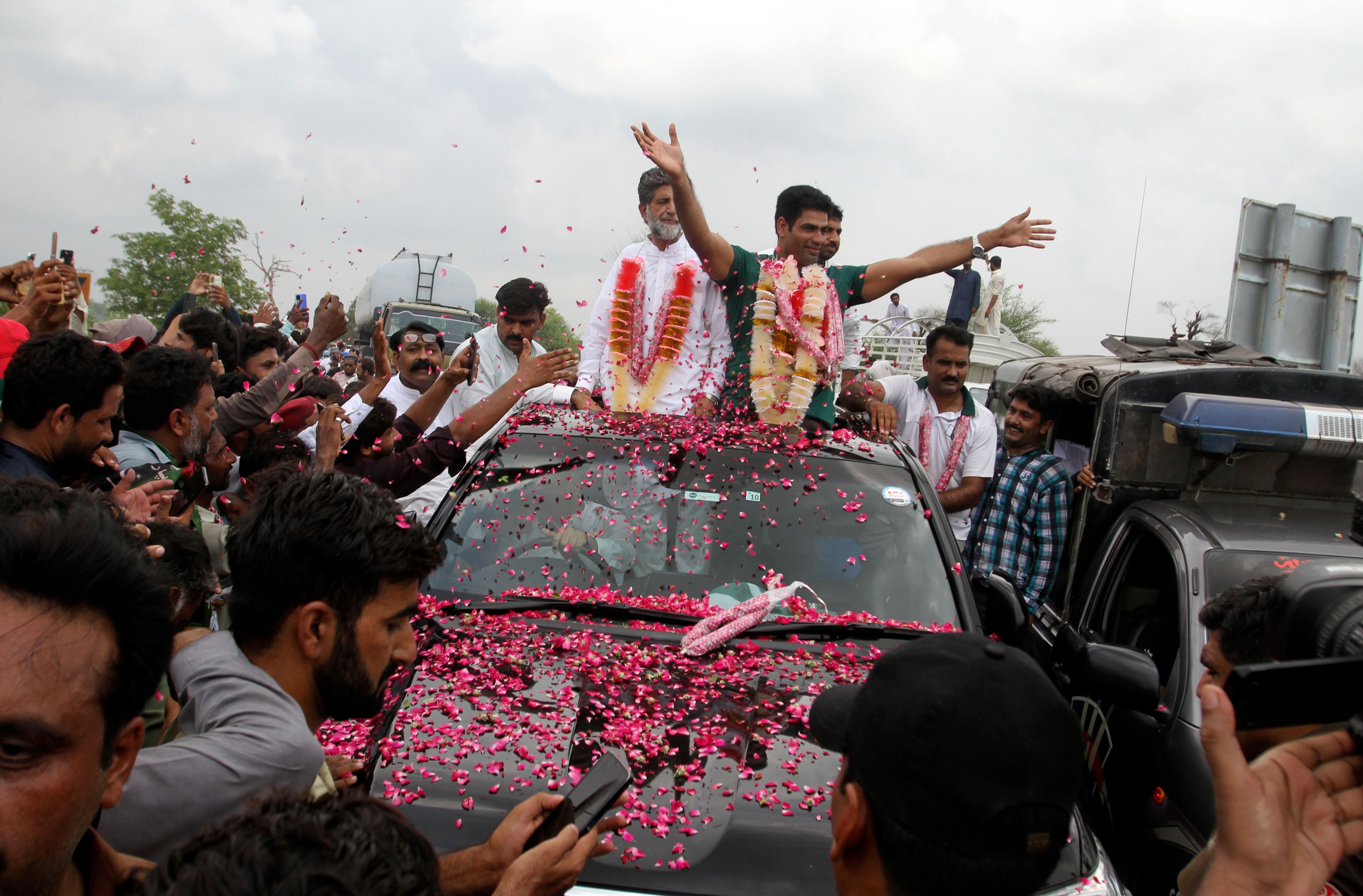 Men's javelin gold medalist, Arshad Nadeem of Pakistan, centre, waves to people outside his village in Mian Channu, Khanewal district, of Pakistan, Sunday, Aug. 11, 2024. (AP Photo/Asim Tanveer)