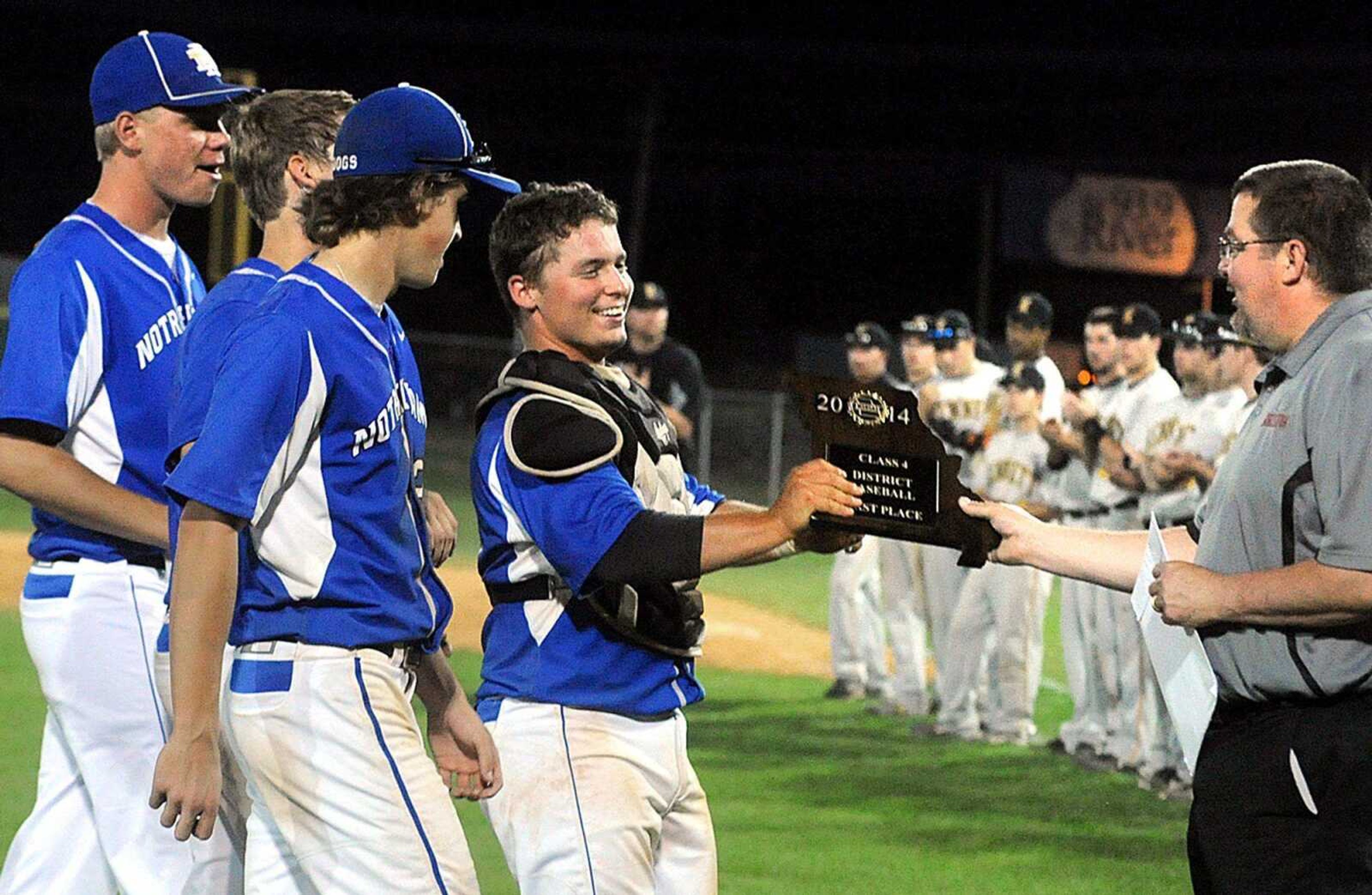 Notre Dame catcher Blake Hagerdorn accepts the Bulldogs' Class 4 District 1 championship trophy from Sikeston High School principal Tim Regenold, Wednesday, May 21, 2014, in Sikeston, Mo. Notre Dame defeated Kennett 12-1. (Laura Simon)