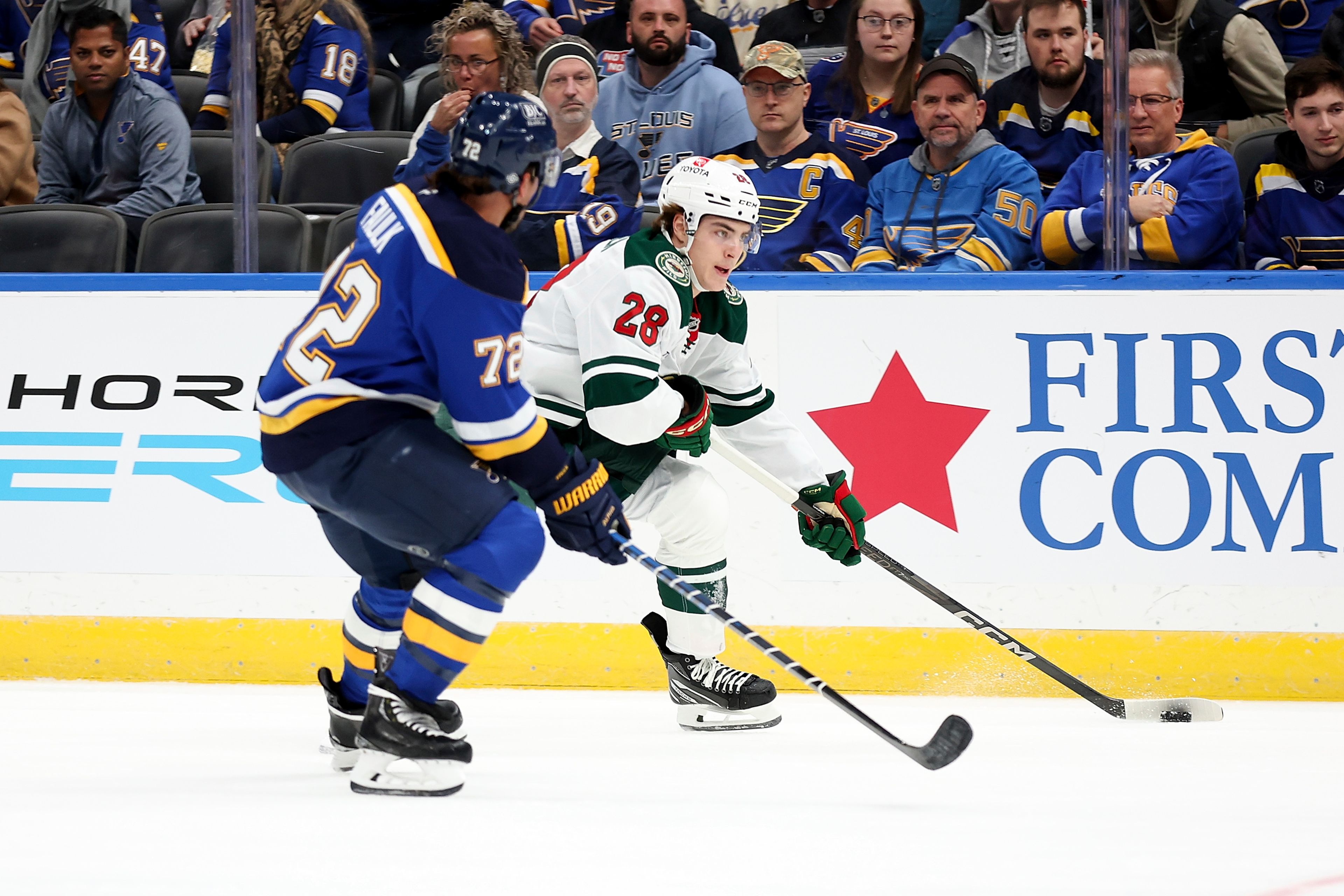 Minnesota Wild's Liam Ohgren (28) controls the puck while under pressure from St. Louis Blues' Justin Faulk (72) during the first period of an NHL hockey game Tuesday, October 15, 2024, in St. Louis. (AP Photo/Scott Kane)