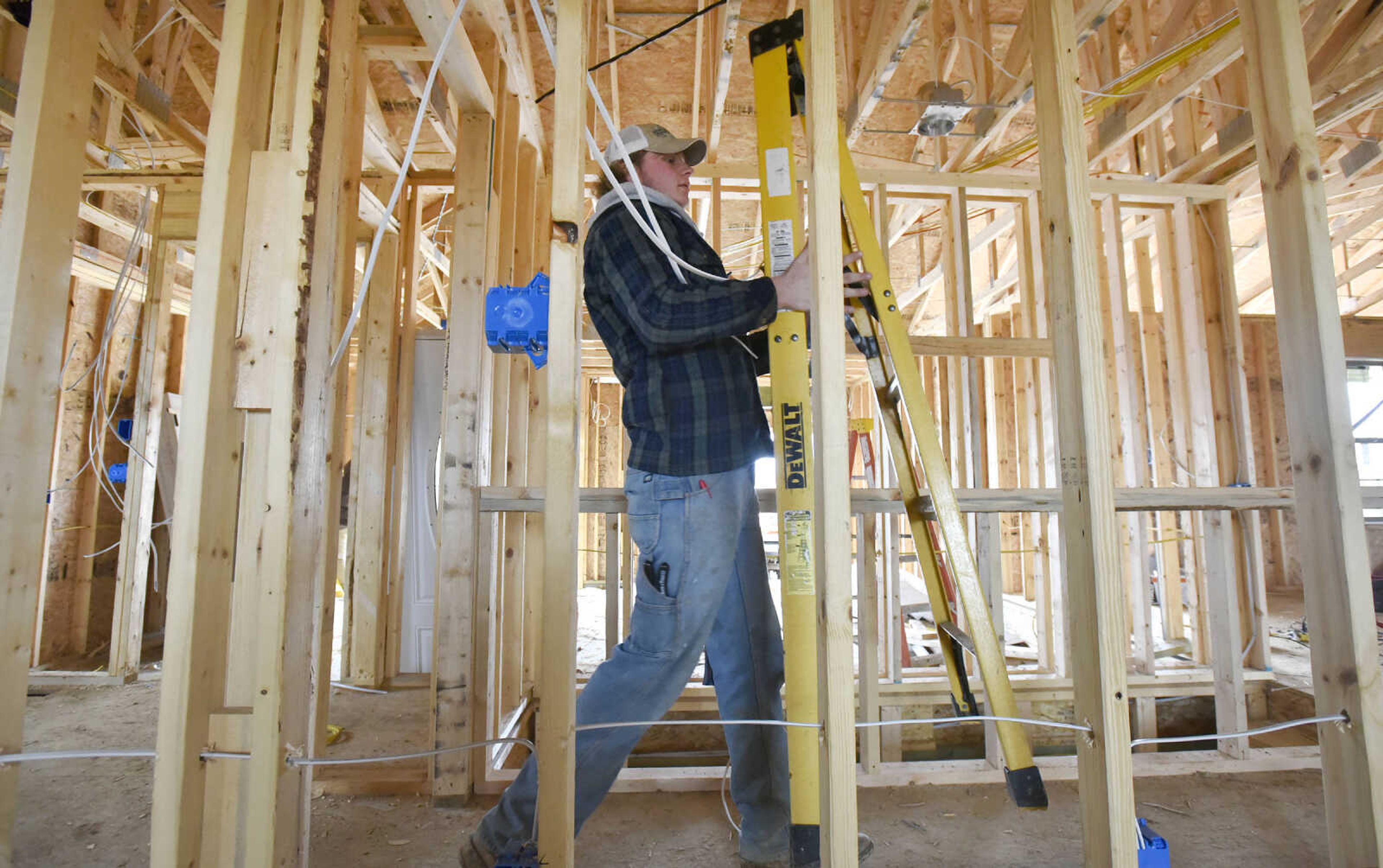 Trey Halter with Southeast Electric, LLC, carries a ladder down the hallway while installing wiring inside a home under construction on Spartan Drive in Jackson on Wednesday, Jan. 18, 2017.