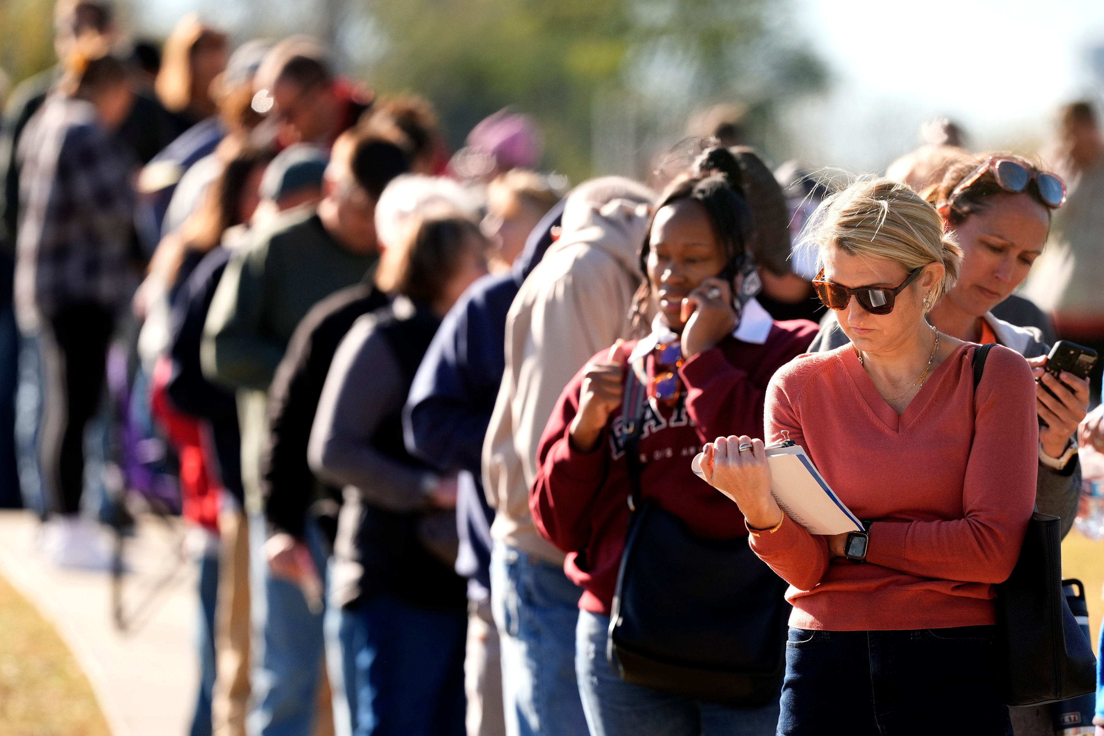 Vanessa Starke, from Lee's Summit, Mo., reads a book about halfway though her 90 minute wait in line to cast her ballot at an early voting location, Thursday, Oct. 31, 2024, in Blue Springs, Mo. (AP Photo/Charlie Riedel)