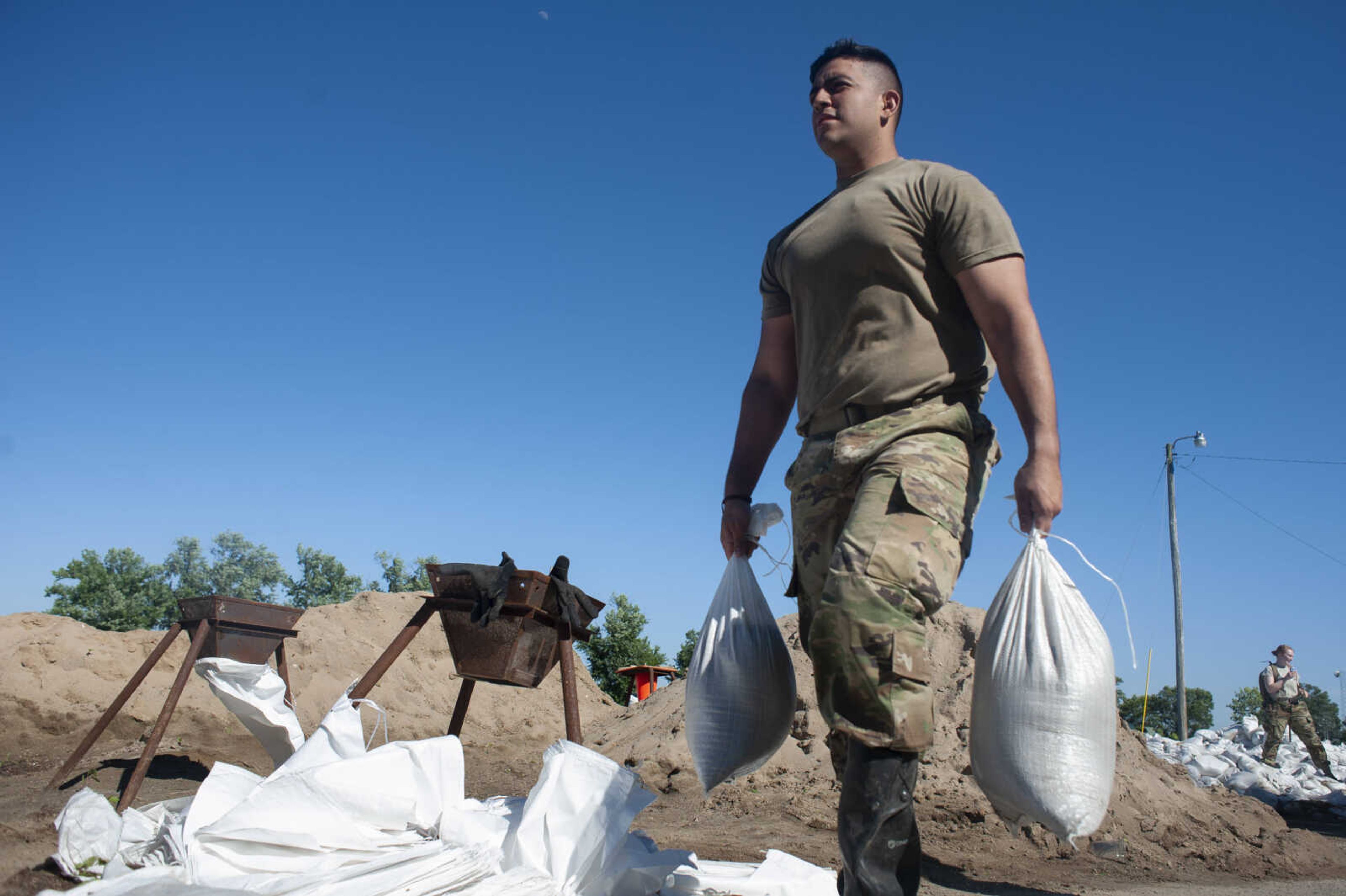 Illinois National Guard member Jesse Aguilera helps build up existing sandbag barriers to hold back floodwaters Monday, June 10, 2019, along Brookwood Drive in East Cape Girardeau, Illinois.