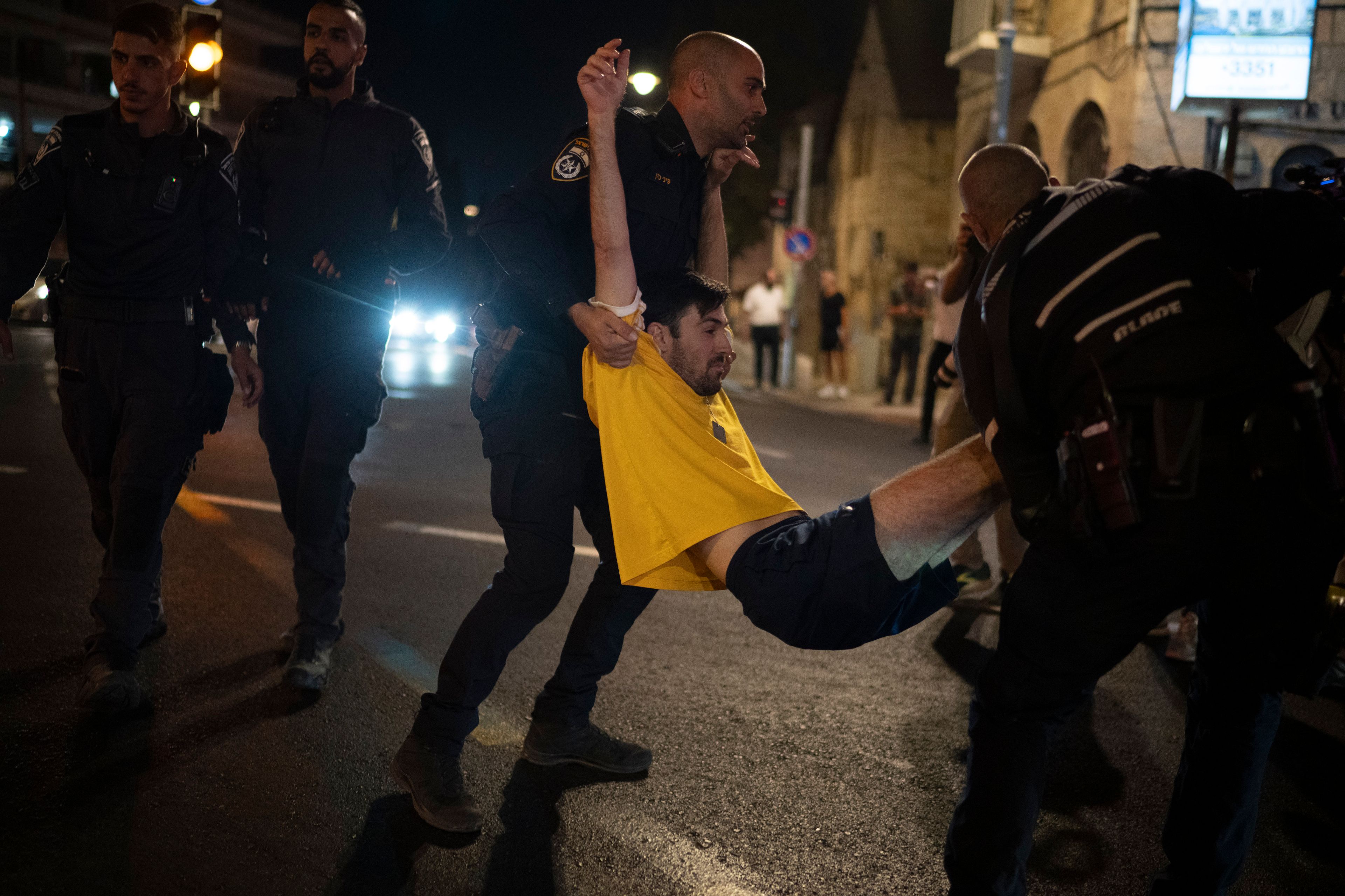 Israeli police officers move a demonstrator blocking a street during a protest, in Jerusalem, Tuesday, Aug. 20, 2024. People gather to honor the memories of six men whose bodies were returned and to call for a deal to release the remaining captives. (AP Photo/Leo Correa)